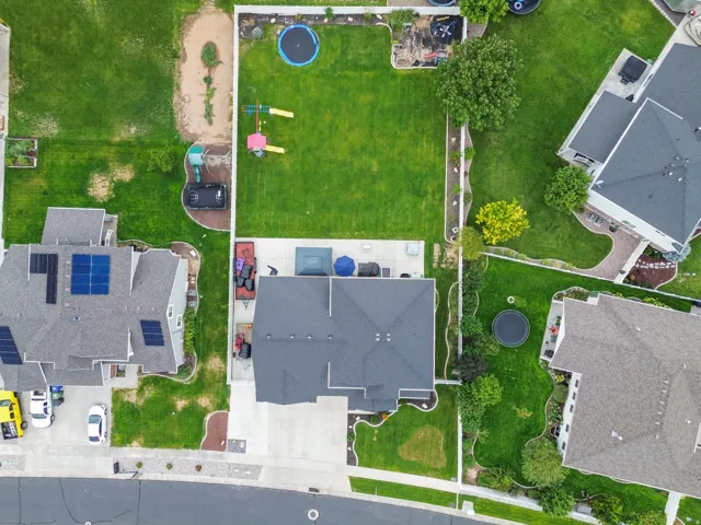 Expansive backyard featuring a manicured lawn, concrete patio, and mature trees