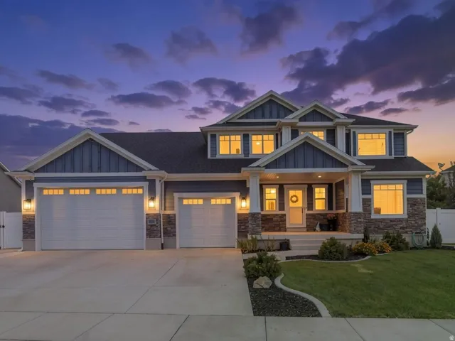 Two-story exterior with multi-toned siding and stone accents, featuring a covered entry, multiple windows, and a concrete driveway leading to two garage doors