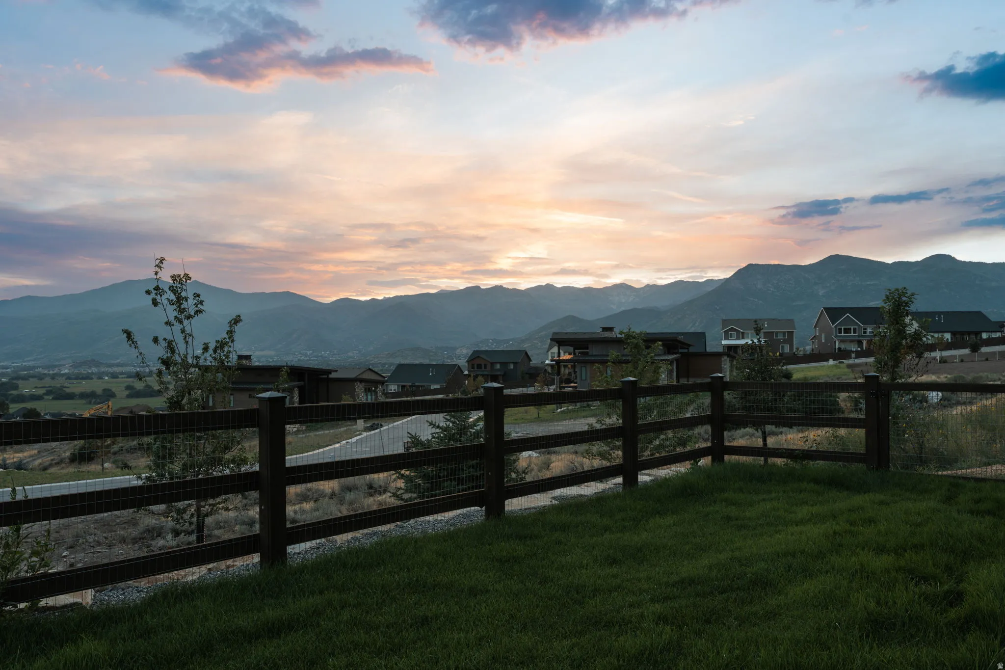 Manicured lawn with a post-and-wire fence, set against a mountain backdrop