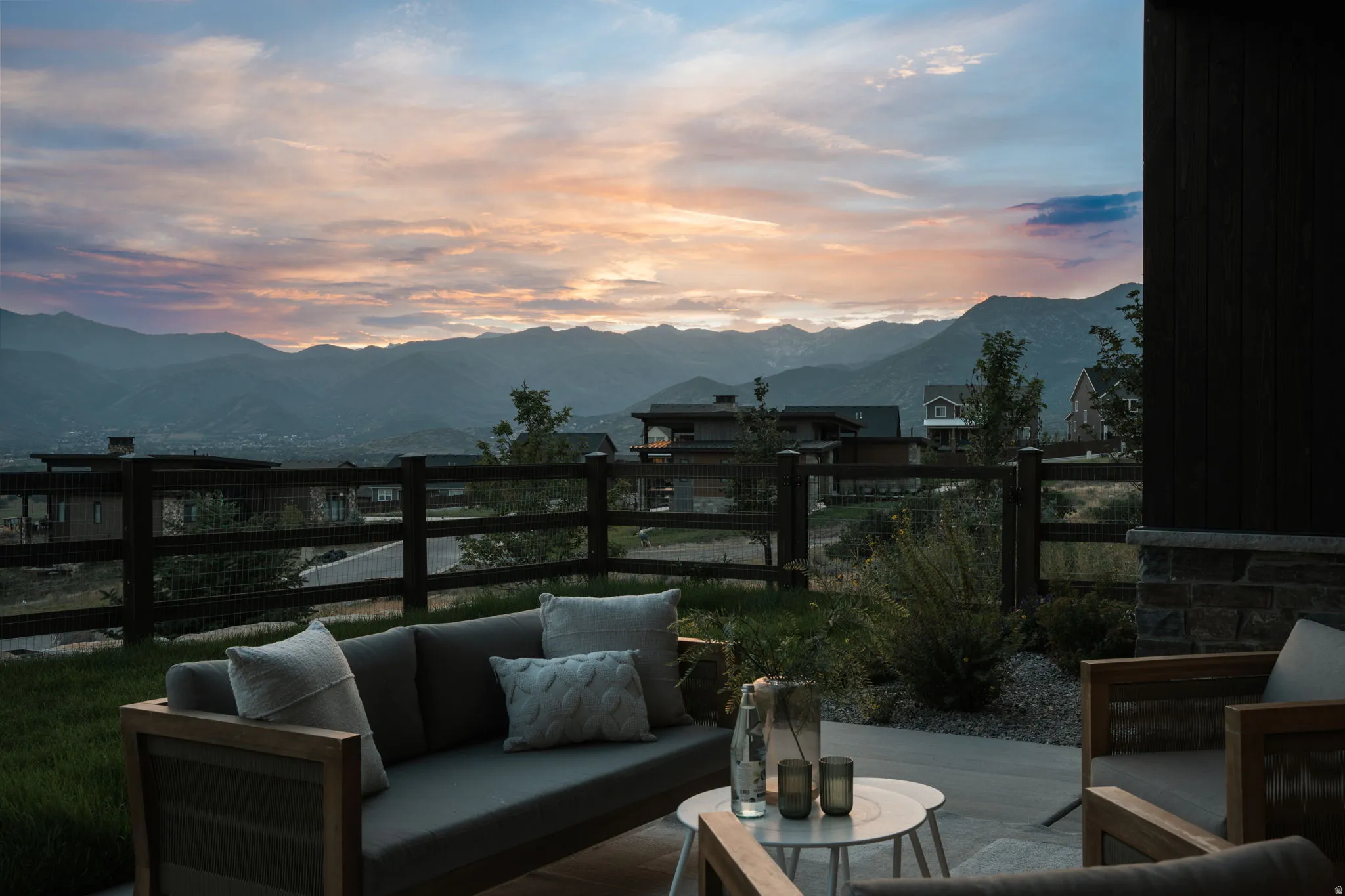 Outdoor patio with a concrete surface, bordered by a wooden fence, and a distant mountain range