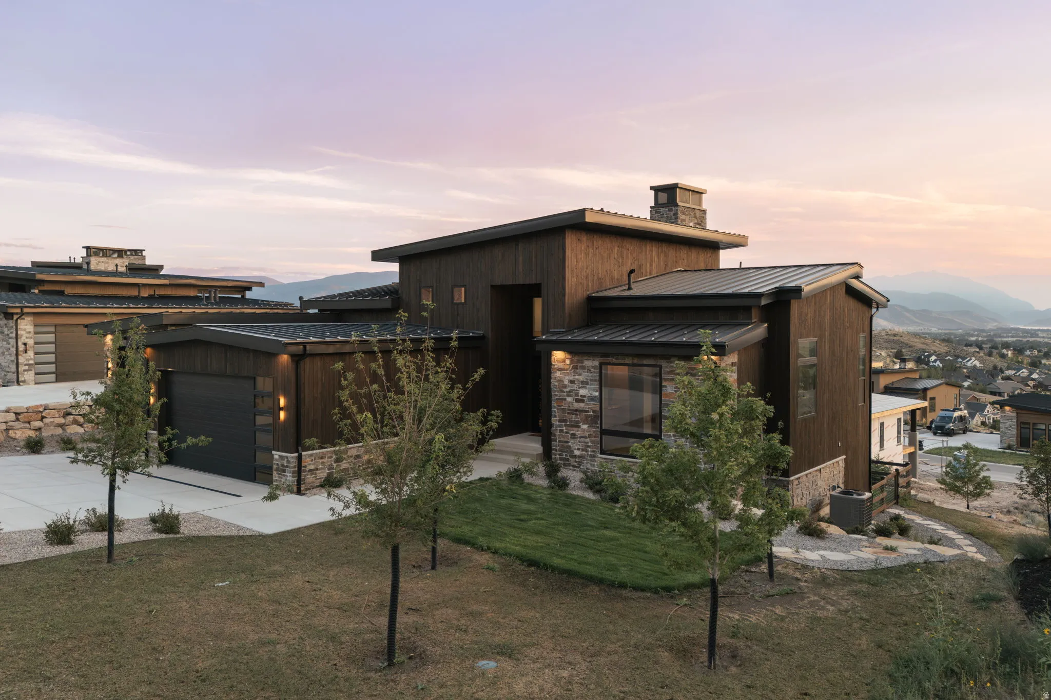 Contemporary exterior featuring dark wood siding, stone accents, and a metal roof