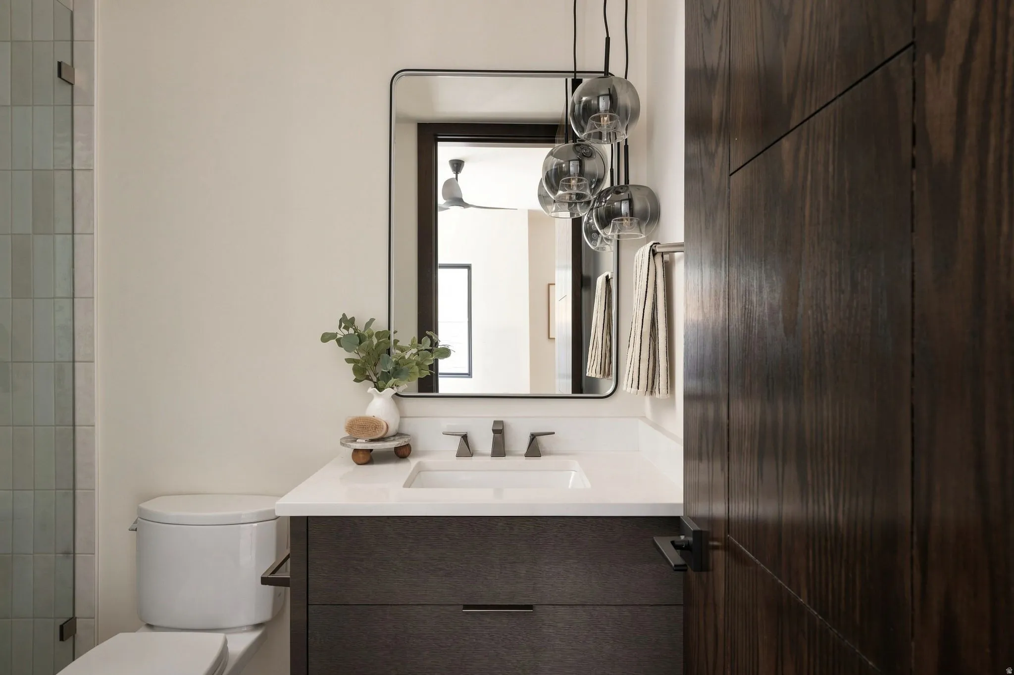 Vanity with white countertop, undermount sink, and dark wood-finish cabinetry