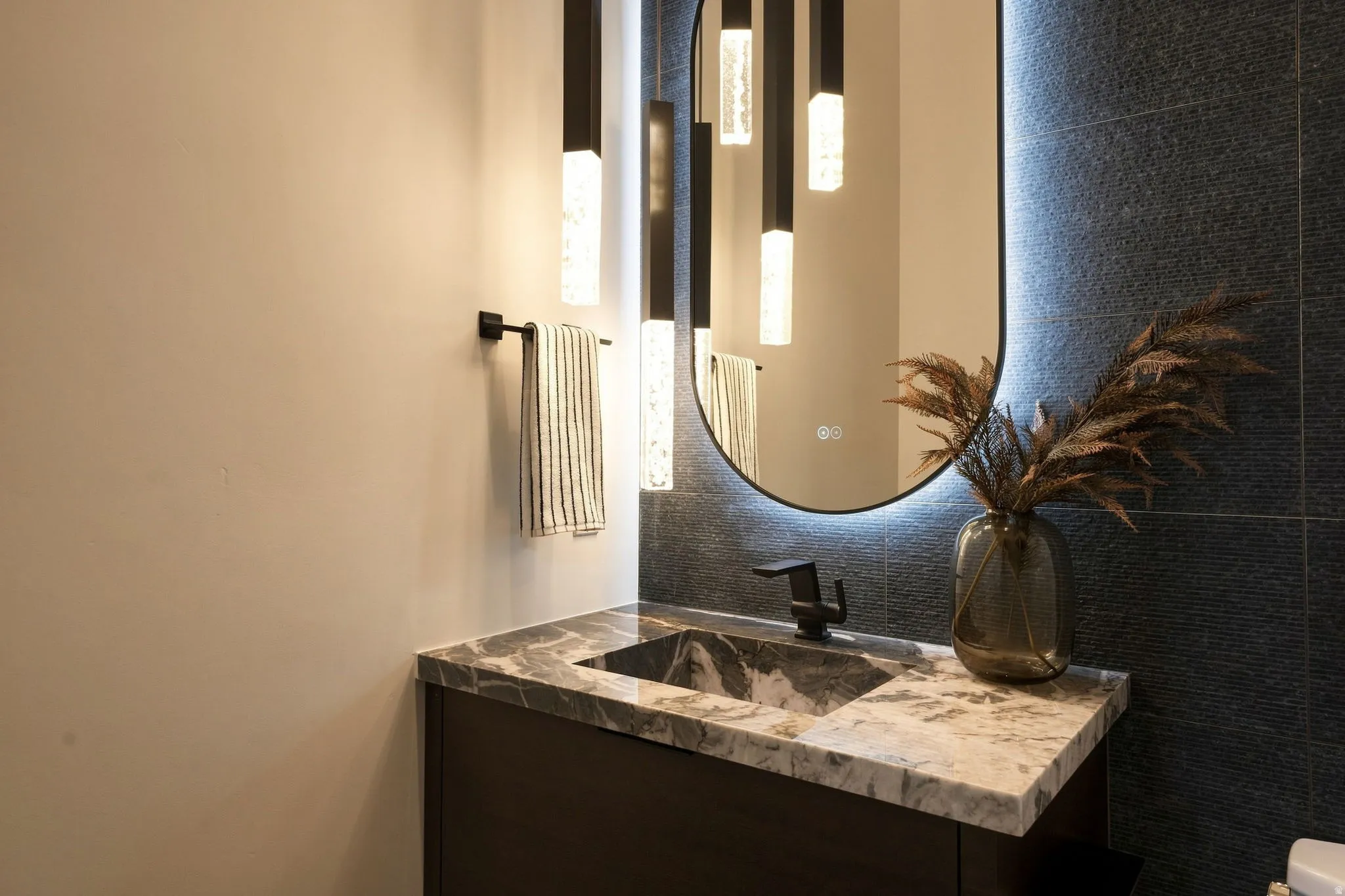Floating vanity with integrated sink, stone countertop, matte black faucet, and backlit mirror
