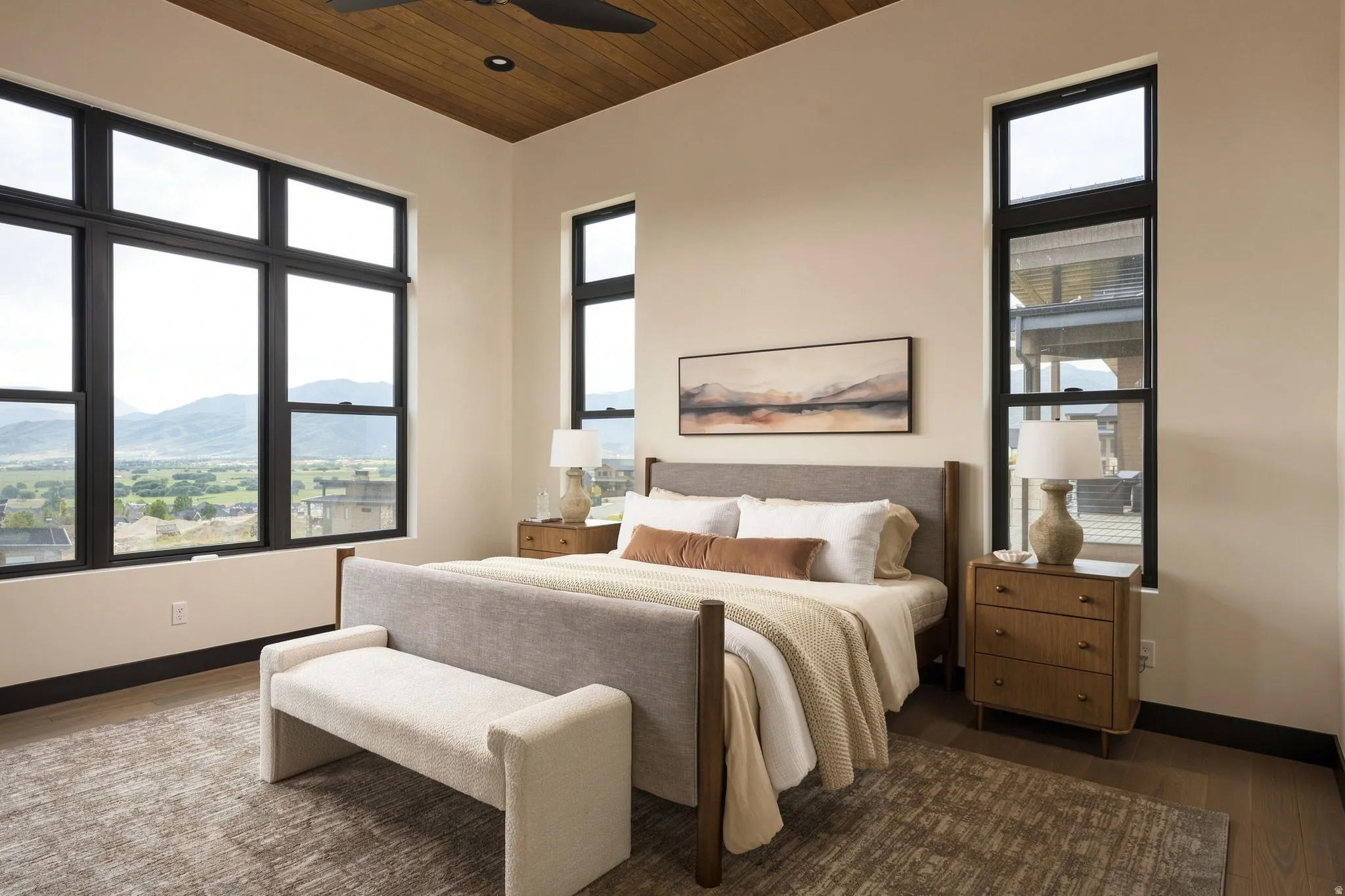 Wood-finish flooring, extensive windows with dark frames, and a wood-paneled ceiling with a ceiling fan