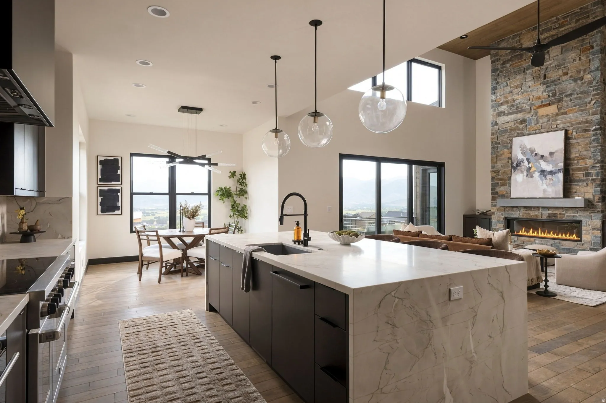 Open-concept living space featuring a stone accent wall, linear fireplace, and ceiling fan