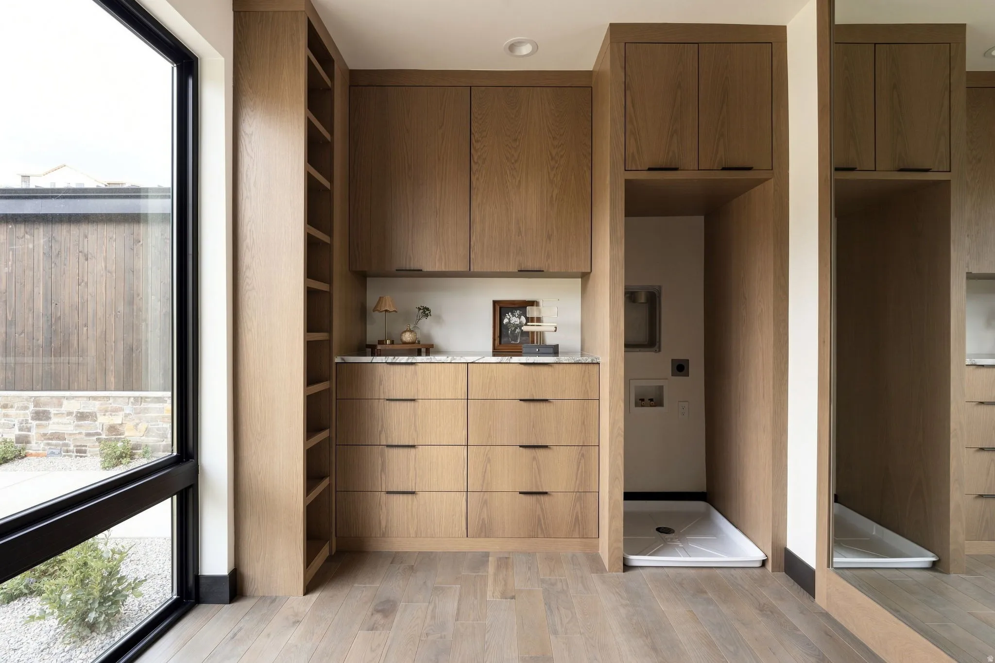 Wood-finish flooring, built-in cabinetry, polished countertop, large fixed-pane window, and recessed lighting