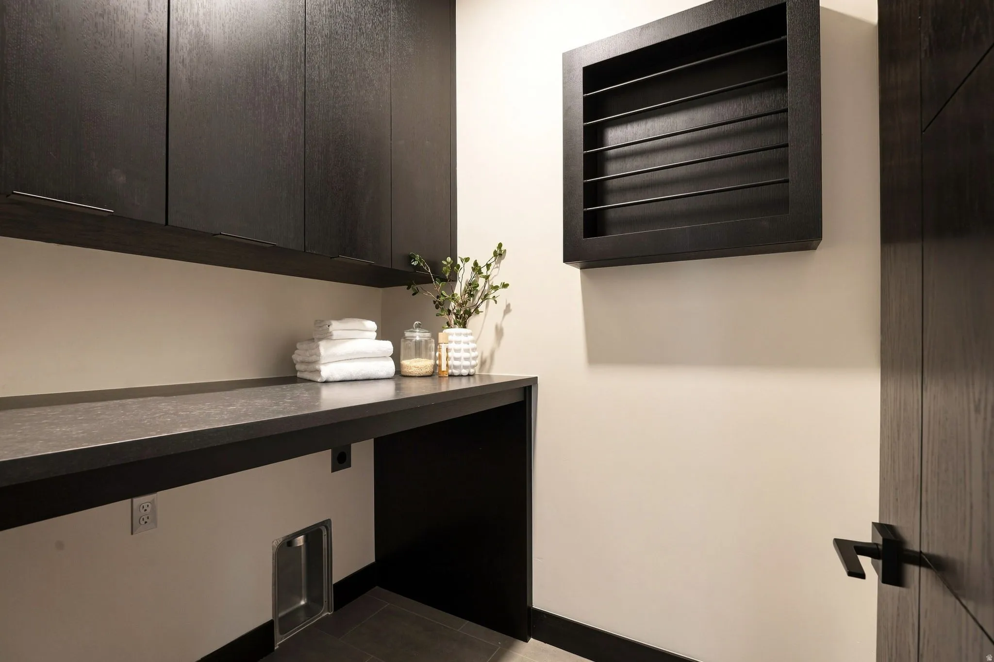 Dark wood-finish cabinetry, built-in wall drying rack, durable countertop, and dark wood-finish door
