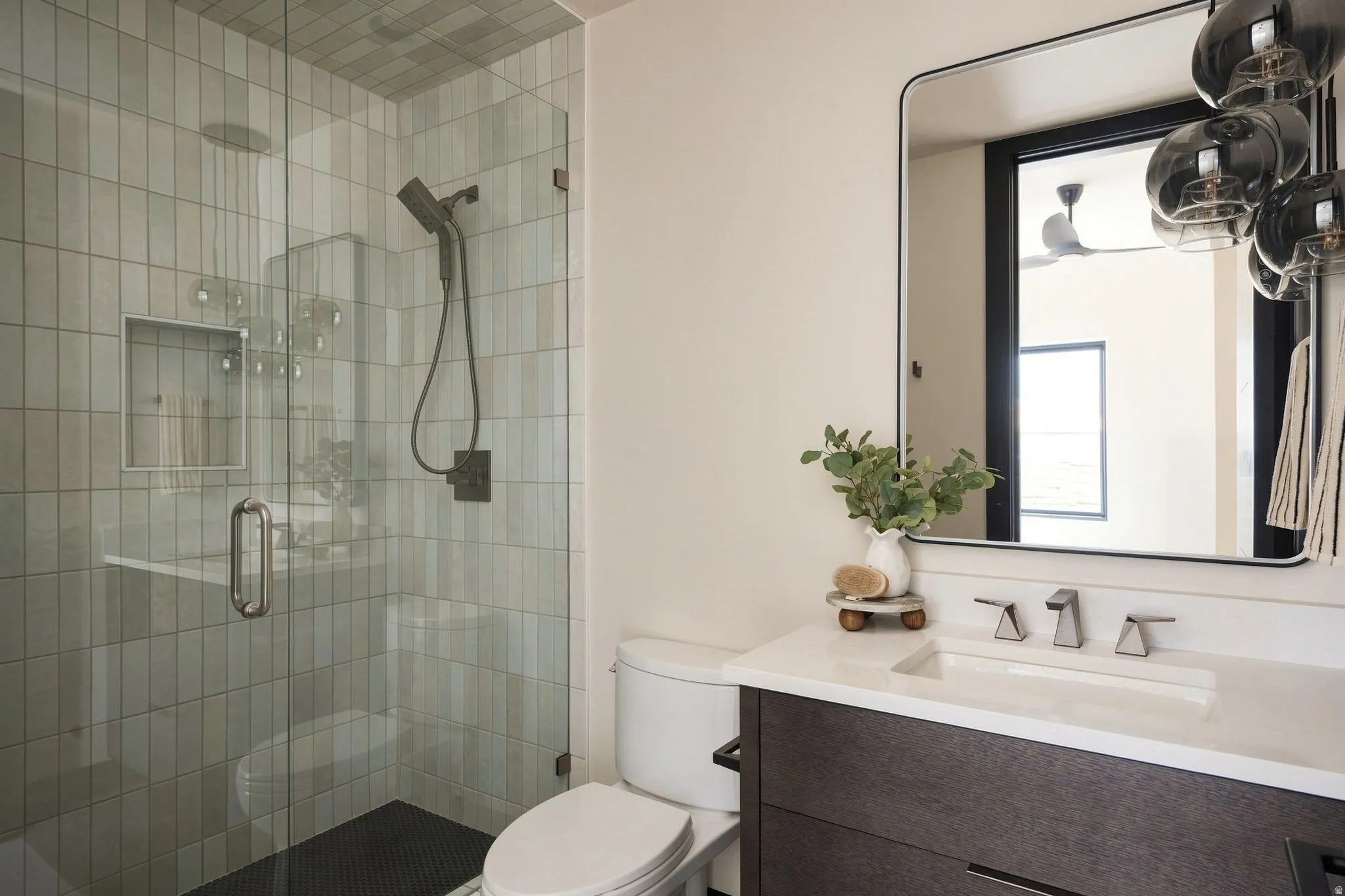Glass-enclosed shower with vertical tile surround and built-in niche