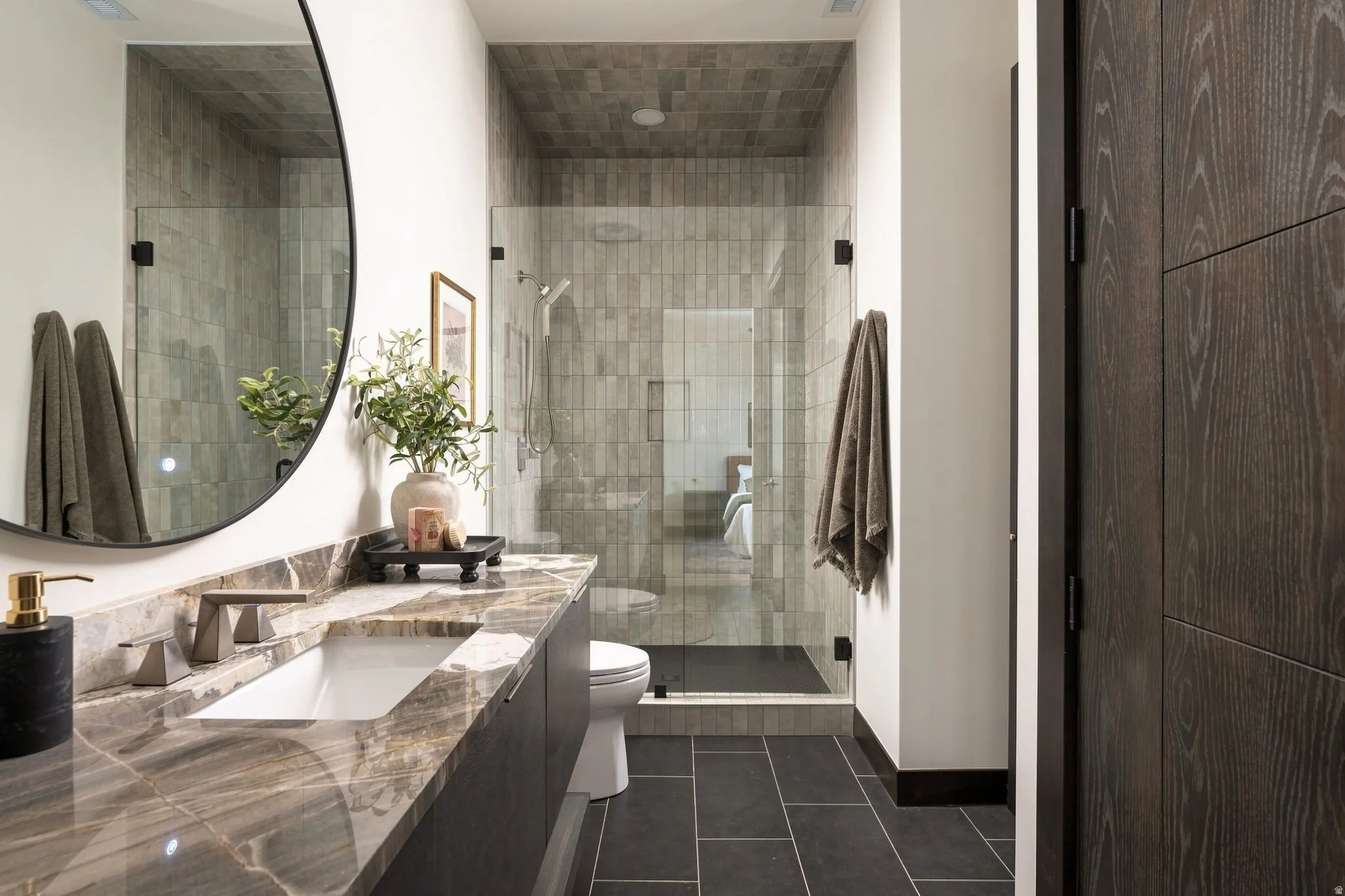Vanity with a rectangular undermount sink, a bronze-finish faucet, and a stone countertop