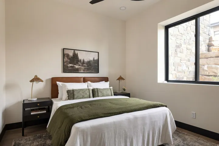 Recessed lighting, sloped ceiling, black-framed window, stone exterior wall, wood-finish flooring