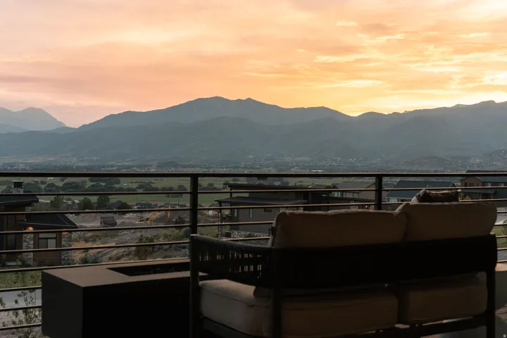 Outdoor terrace with horizontal metal railing, featuring a built-in rectangular fire pit and broad mountain scenery