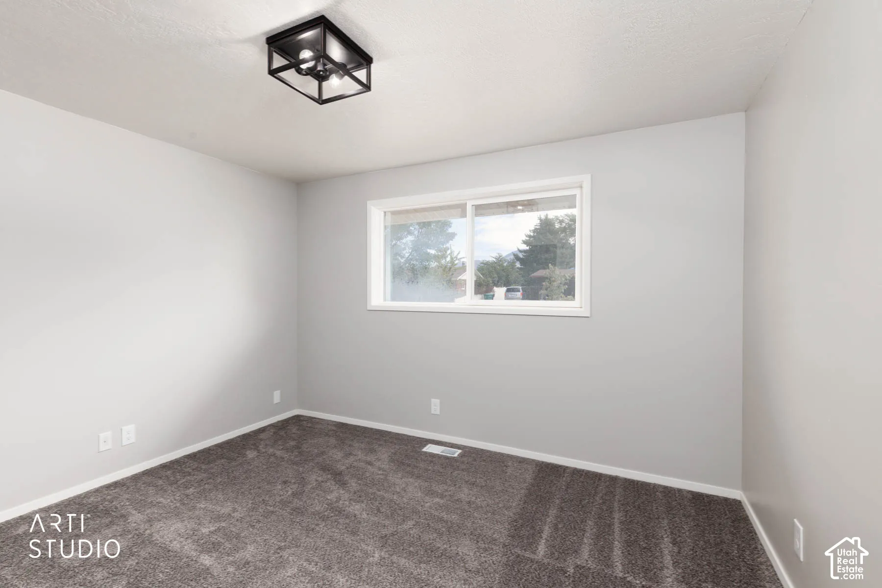 Neutral tone walls, textured ceiling, flush mount light fixture, white trim, and carpeted flooring