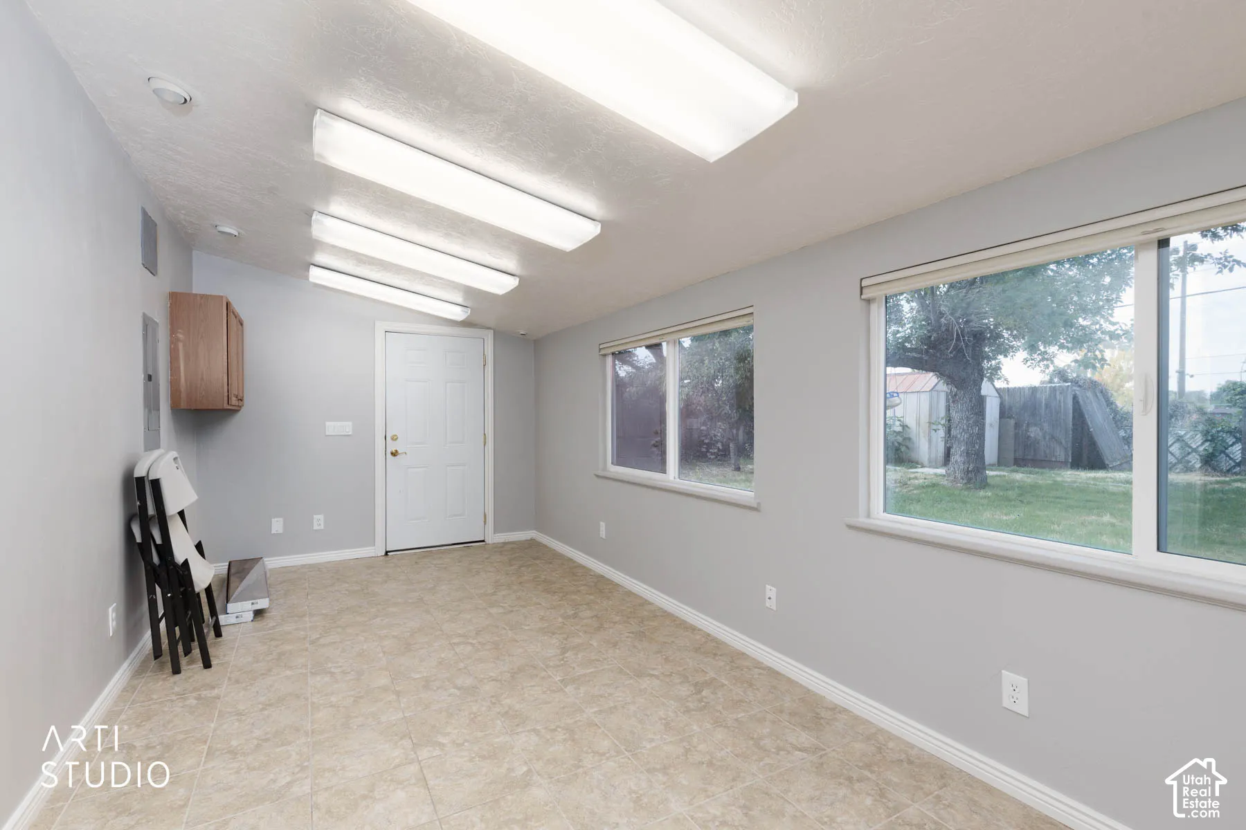 Neutral-toned tile flooring, light gray walls, white trim, and multiple fluorescent ceiling lights
