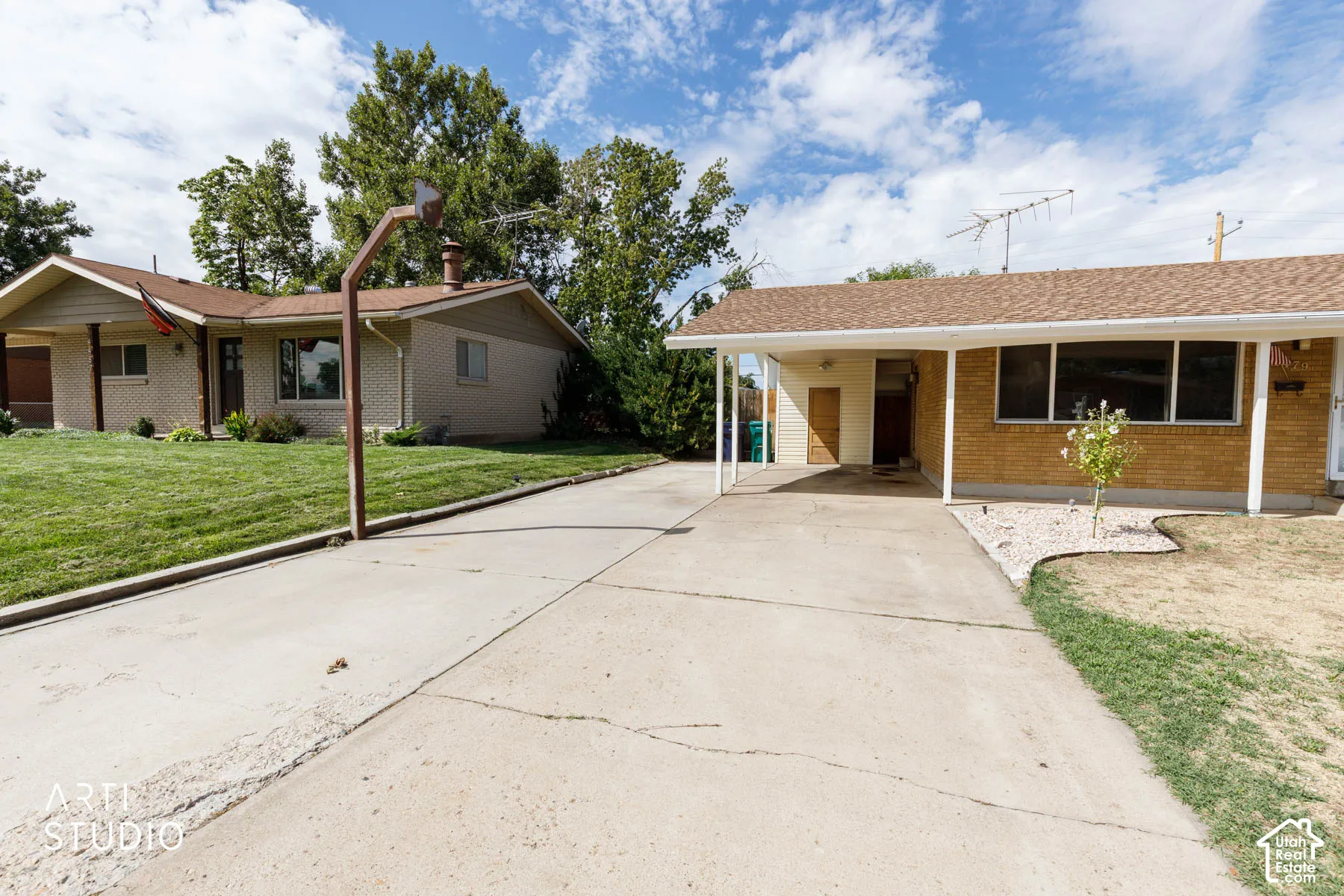 Carport structure, brick exterior accents, established landscaping, and a concrete driveway