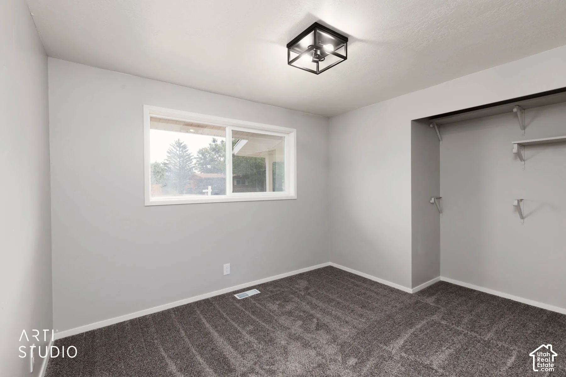 Light gray walls, dark gray carpet, white trim, and a white-framed window