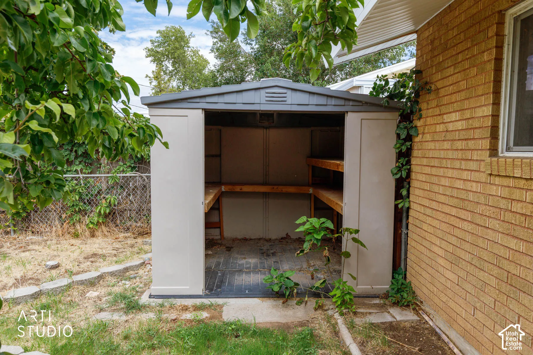 Compact outdoor storage shed with a peaked roof and integrated shelving