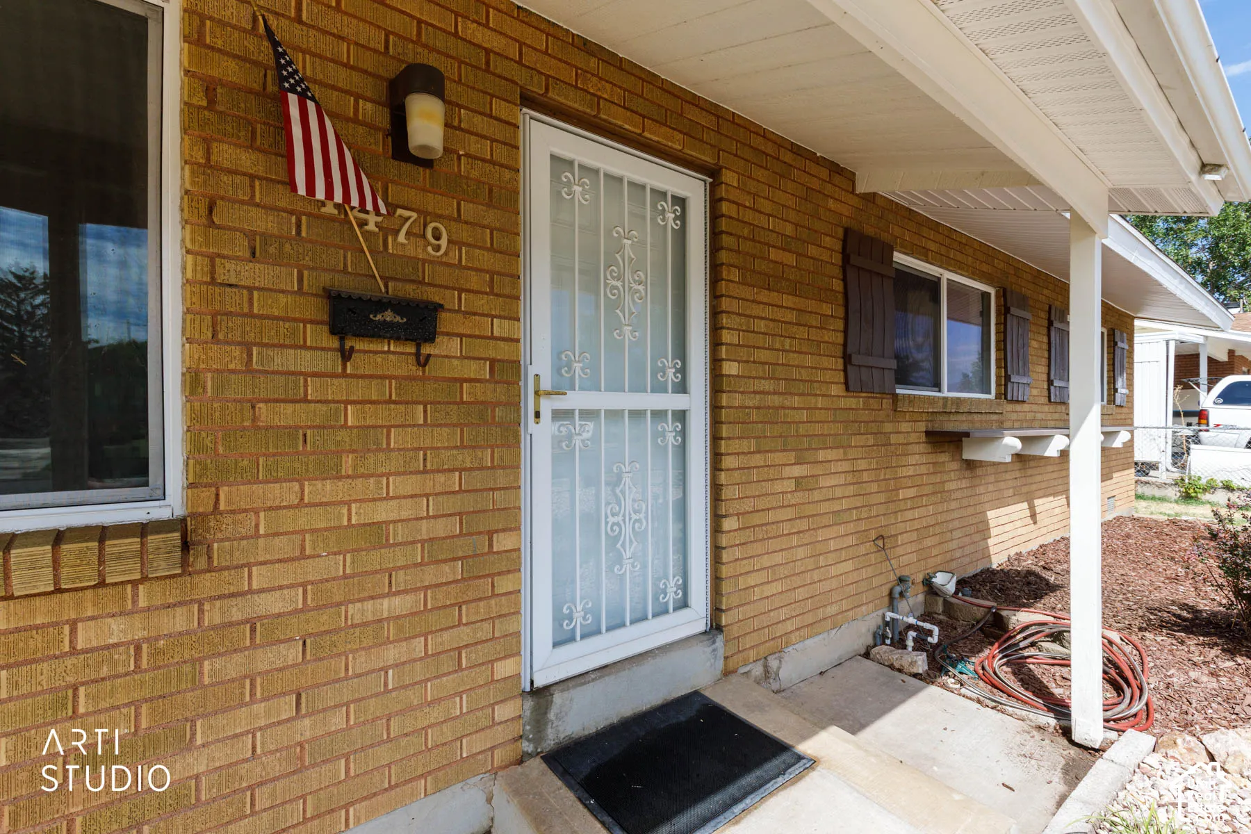 Brick exterior with a white storm door, covered entry, and decorative shutters