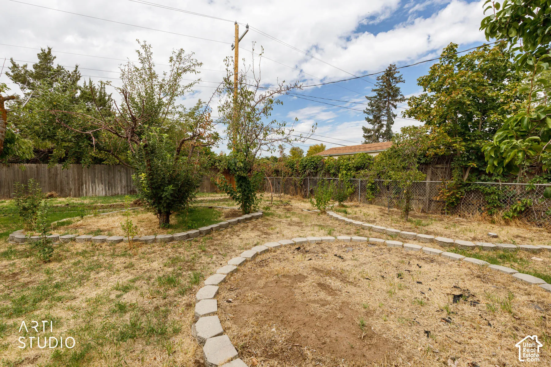 Expansive backyard featuring mature trees, a wood privacy fence, and a chain-link fence