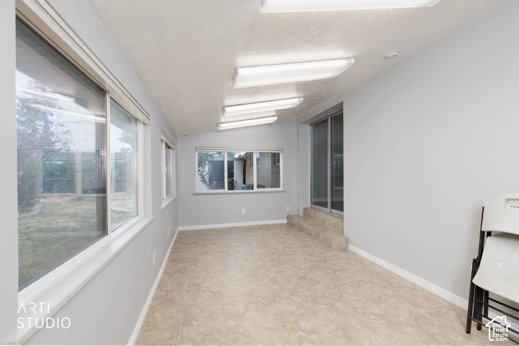 Sunroom with multiple windows, recessed lighting, tile flooring, and sliding glass door access