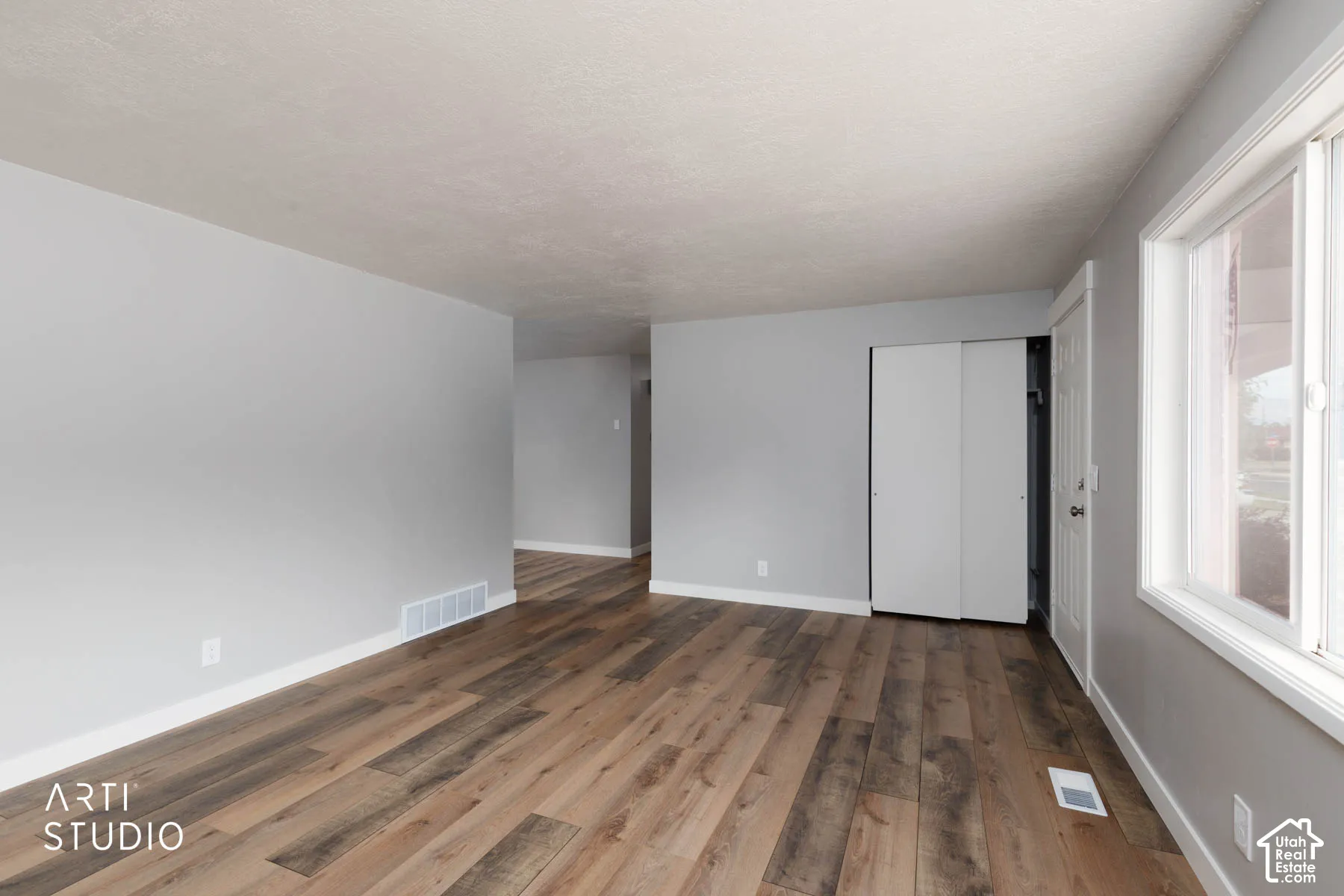 Wood-finish flooring, light gray walls, white trim, and a window with white casing