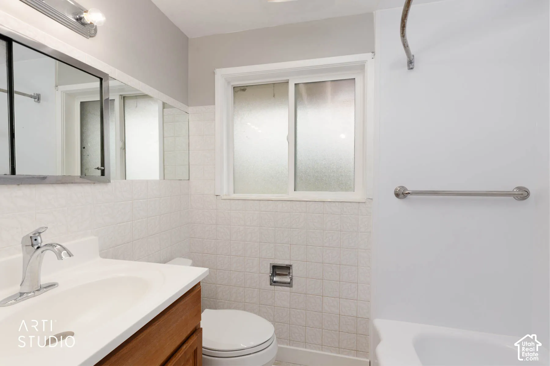 Bathroom featuring a wood-finish vanity with an integrated white sink, chrome fixtures, and a medicine cabinet with mirrored doors