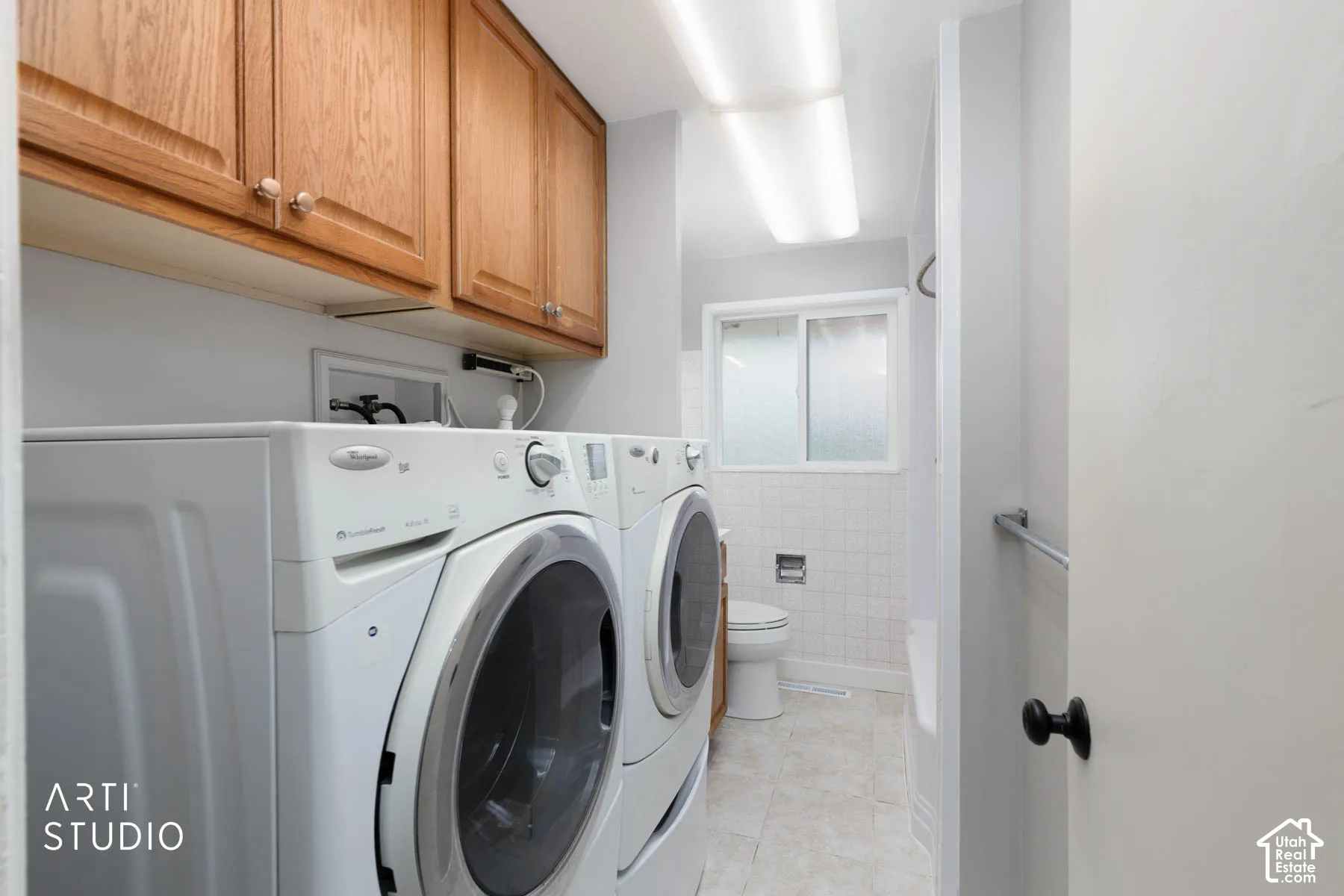 Laundry area featuring wood cabinetry, overhead fluorescent lighting, and a frosted glass window