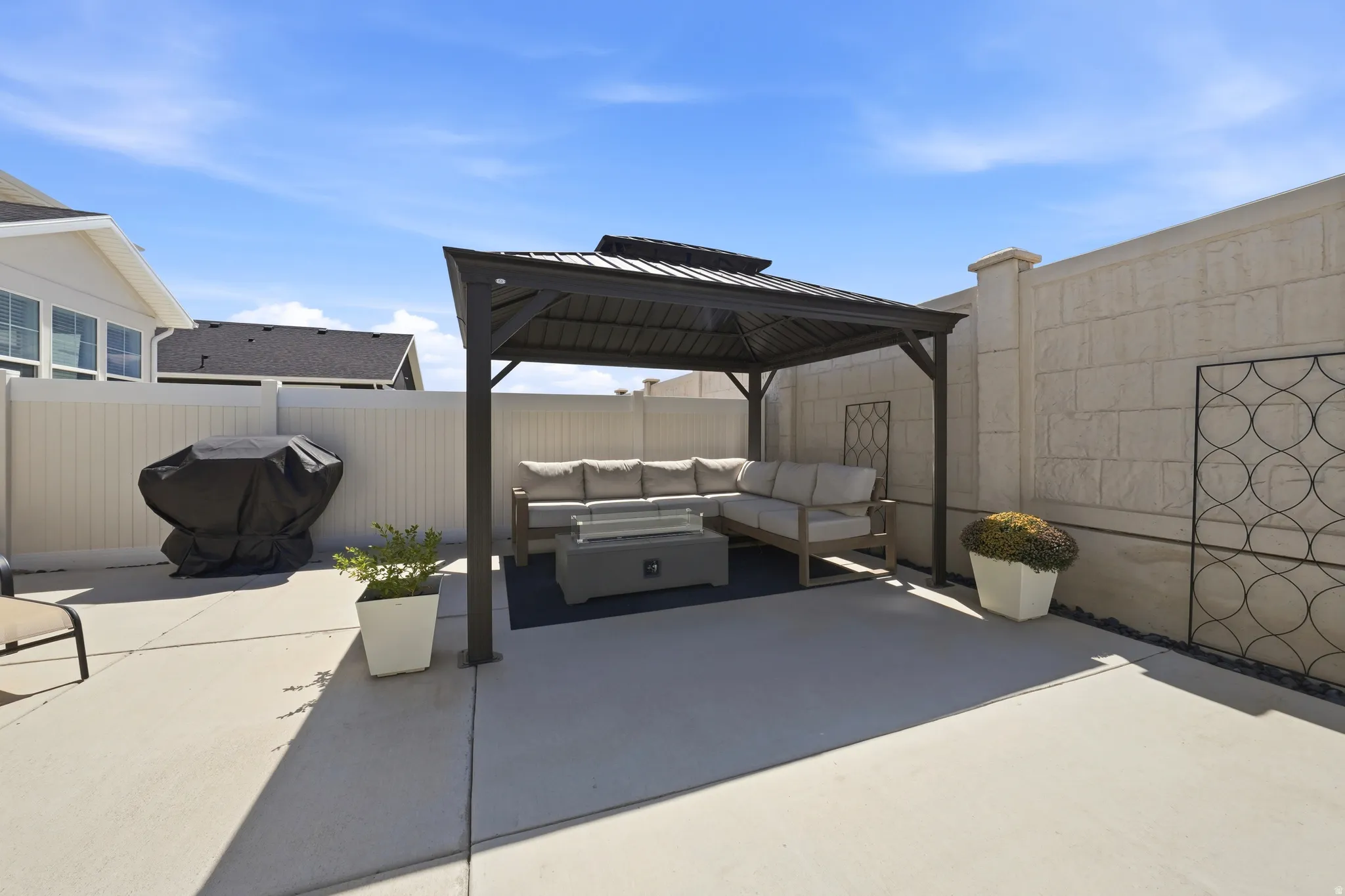 Paved patio with a metal gazebo and a privacy fence