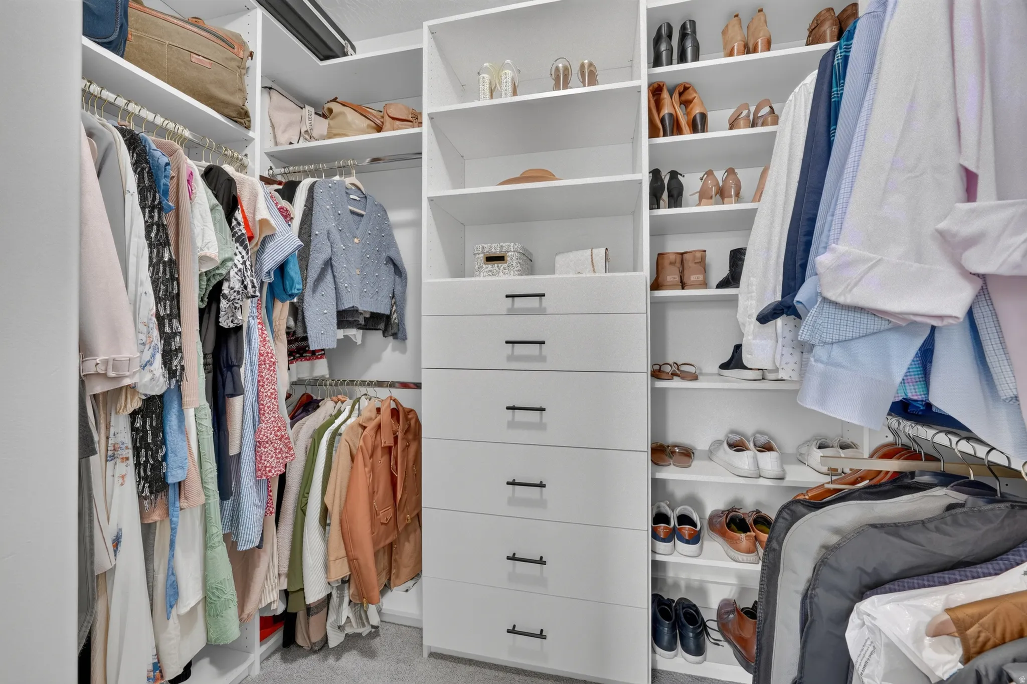 Custom closet system with white shelving, integrated drawers, and multiple hanging rods