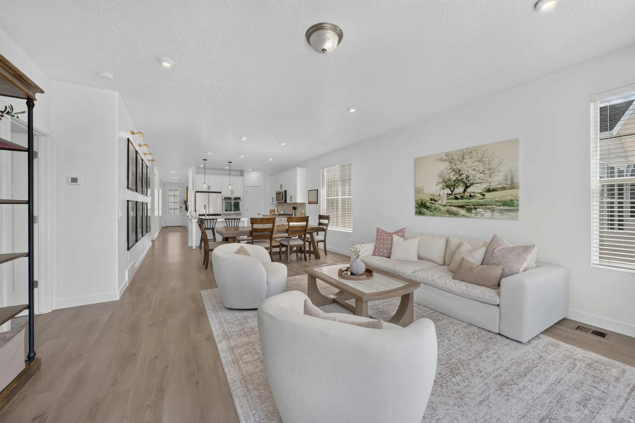 Open-concept living area featuring wood-finish flooring, recessed lighting, and multiple windows