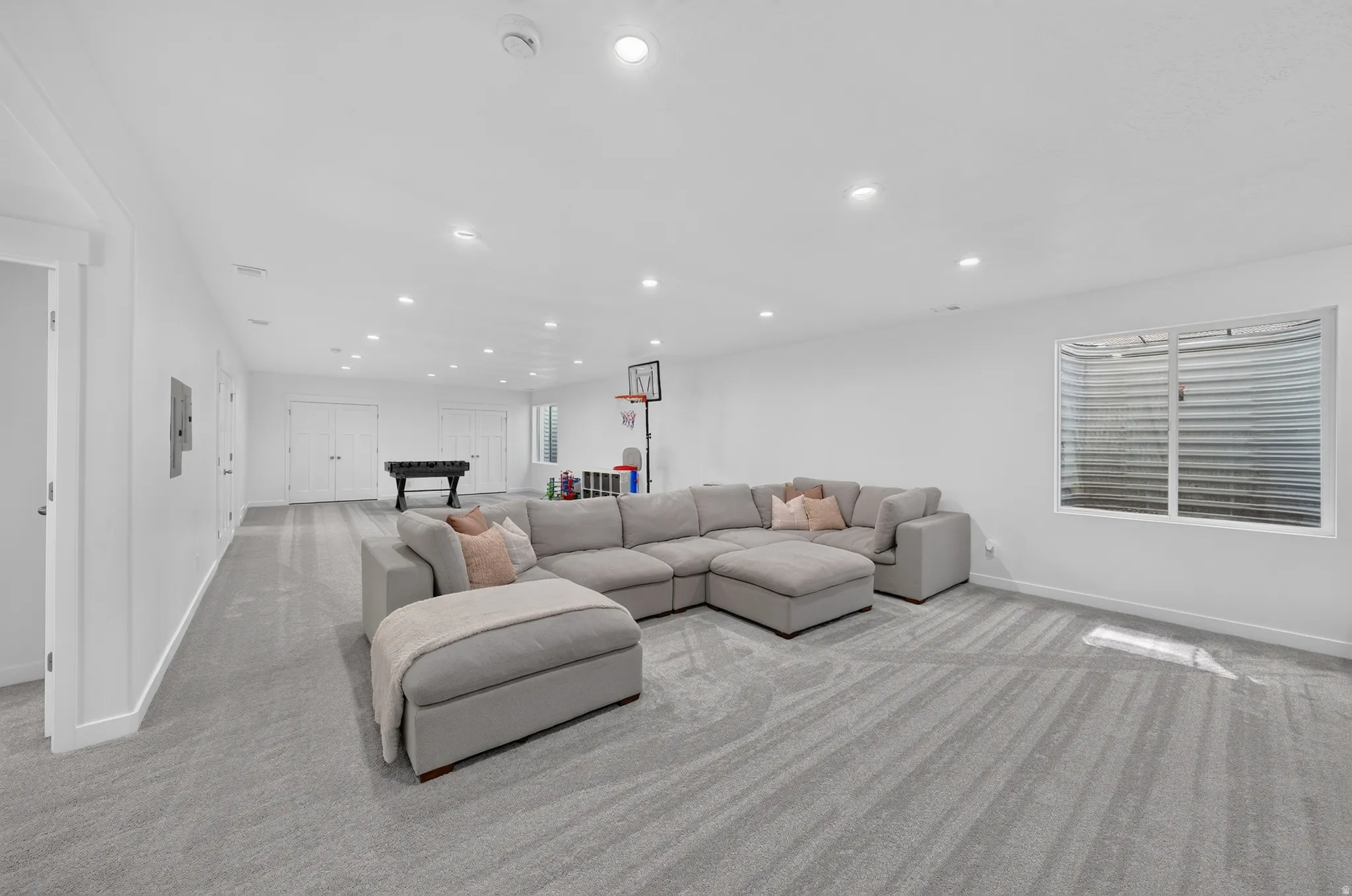 Expansive interior space featuring light grey carpet, recessed lighting, and white walls