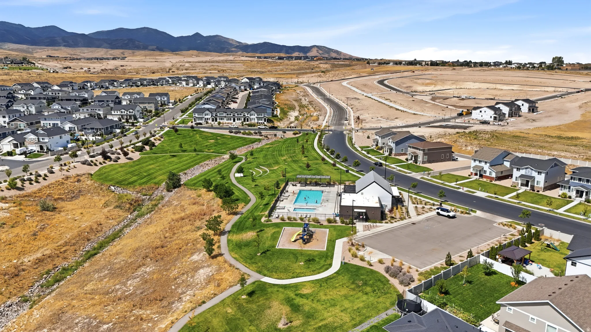 Community park with manicured lawns, a swimming pool, and a playground structure