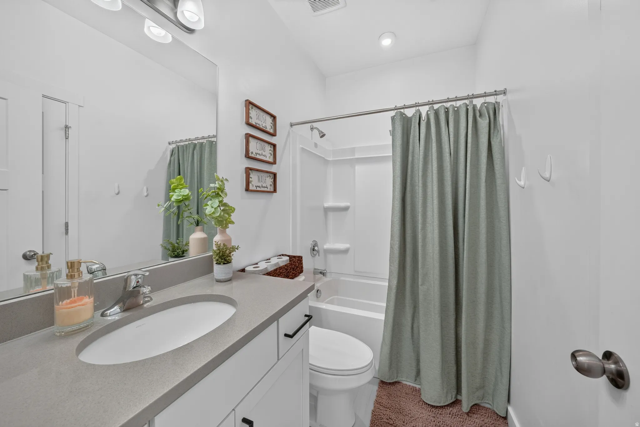 Full-size mirror, single vanity with a solid surface countertop, integrated sink, and white cabinetry with dark hardware
