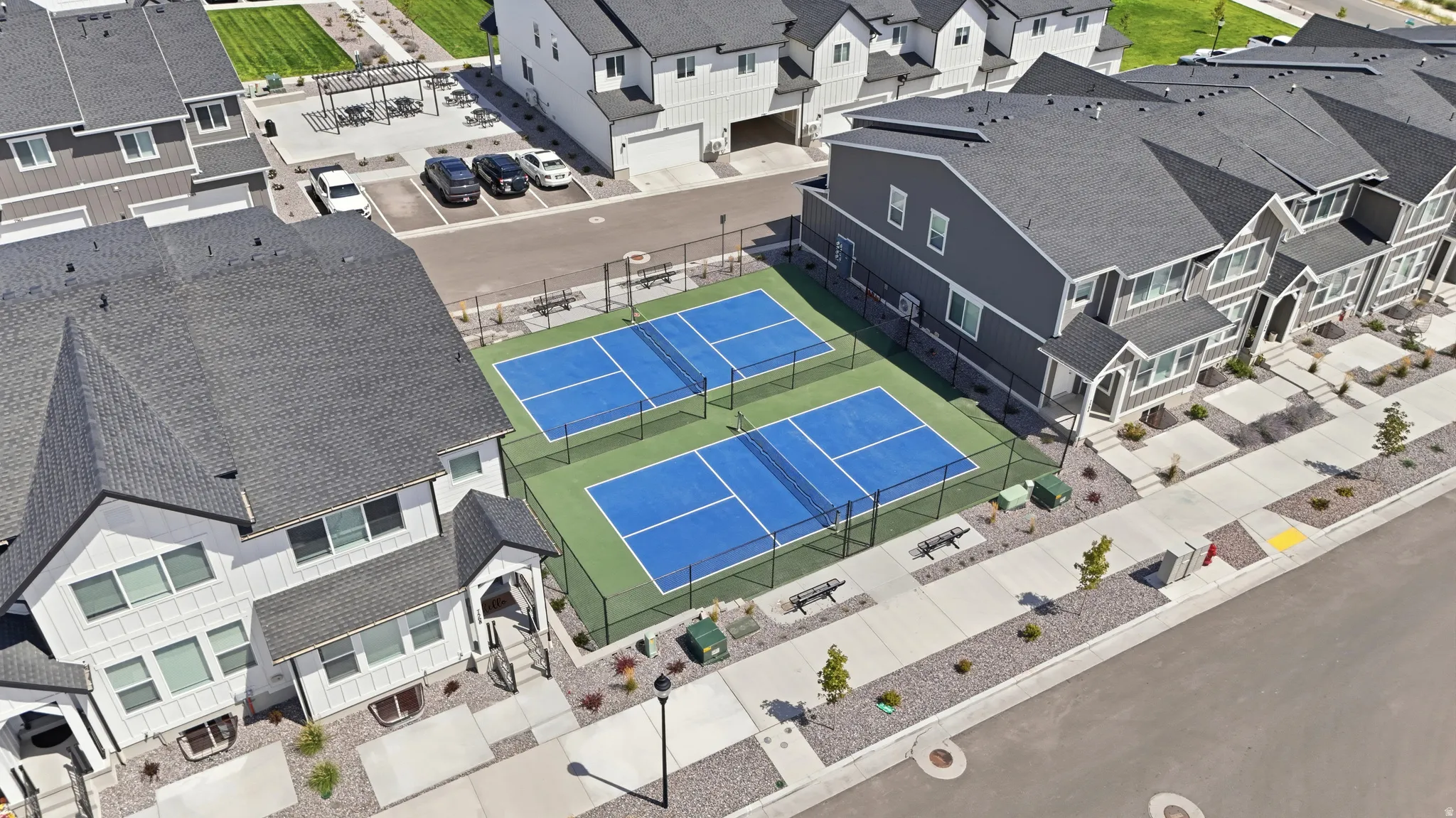 Two fenced pickleball courts, surrounding sidewalks, and landscaped areas