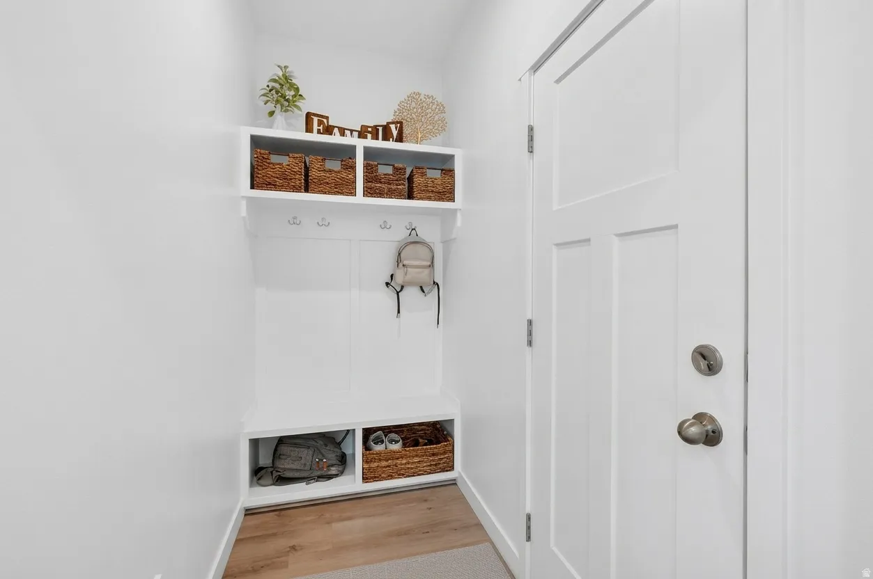 Built-in mudroom storage with an integrated bench, upper shelving, and lower cubbies, complemented by wood-finish flooring