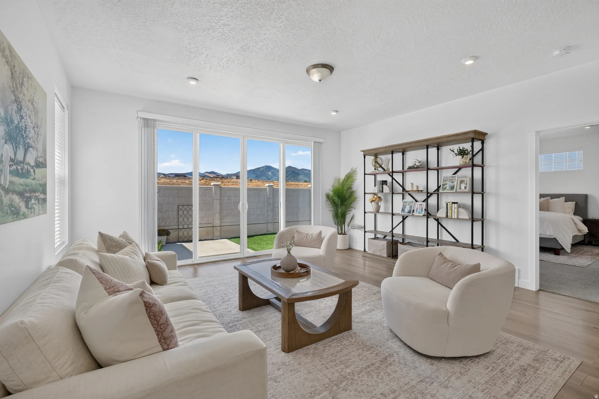 Sliding glass doors, recessed lighting, wood-finish flooring, and a decorative shelving unit