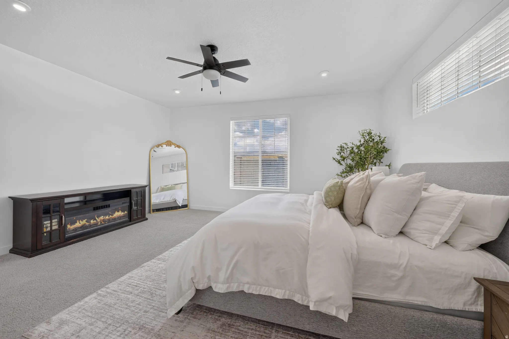 Recessed lighting, ceiling fan, carpet flooring, large window with horizontal blinds, built-in electric fireplace unit