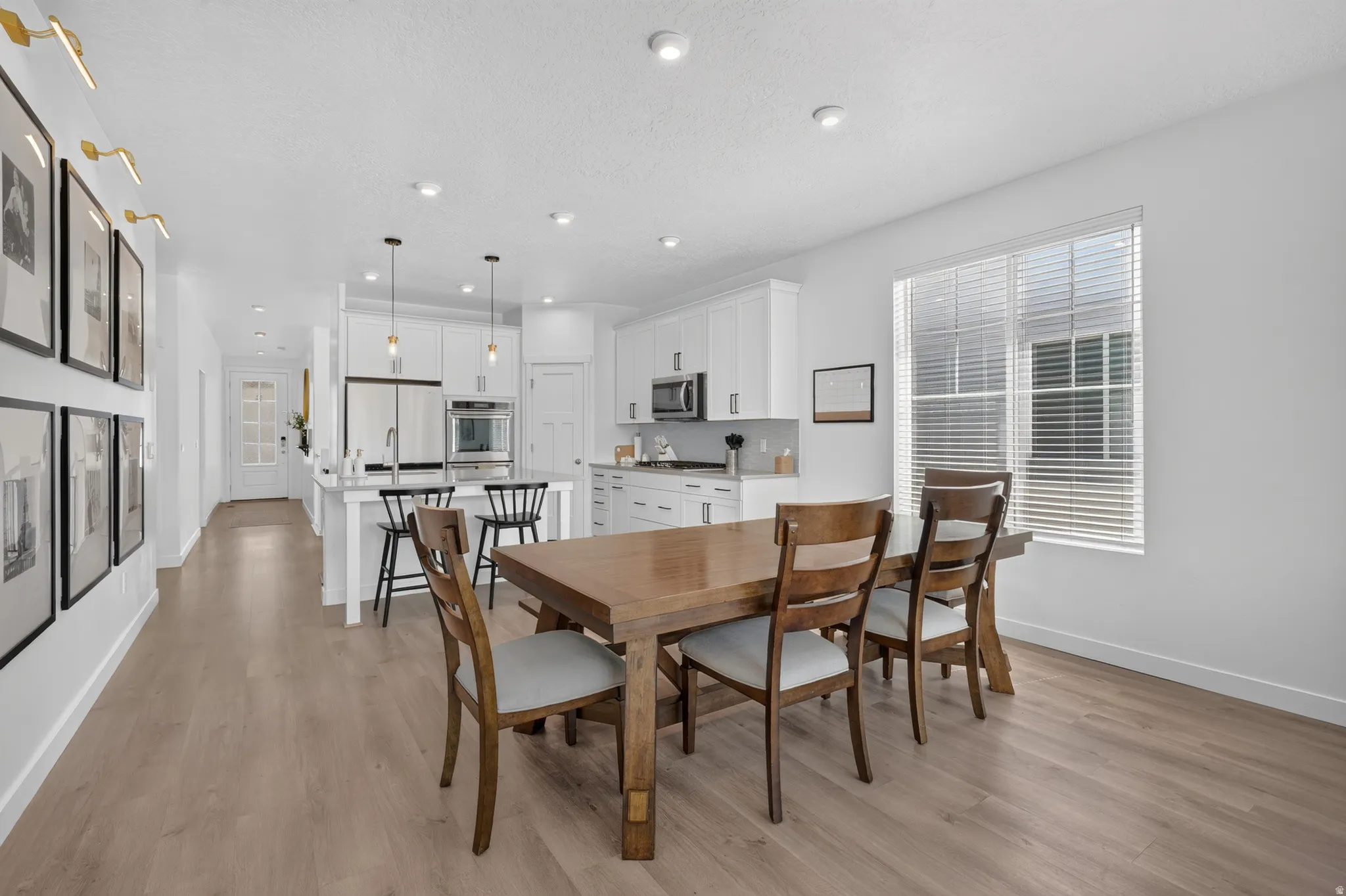 Open-concept dining area with wood-finish flooring, recessed lighting, and a large window