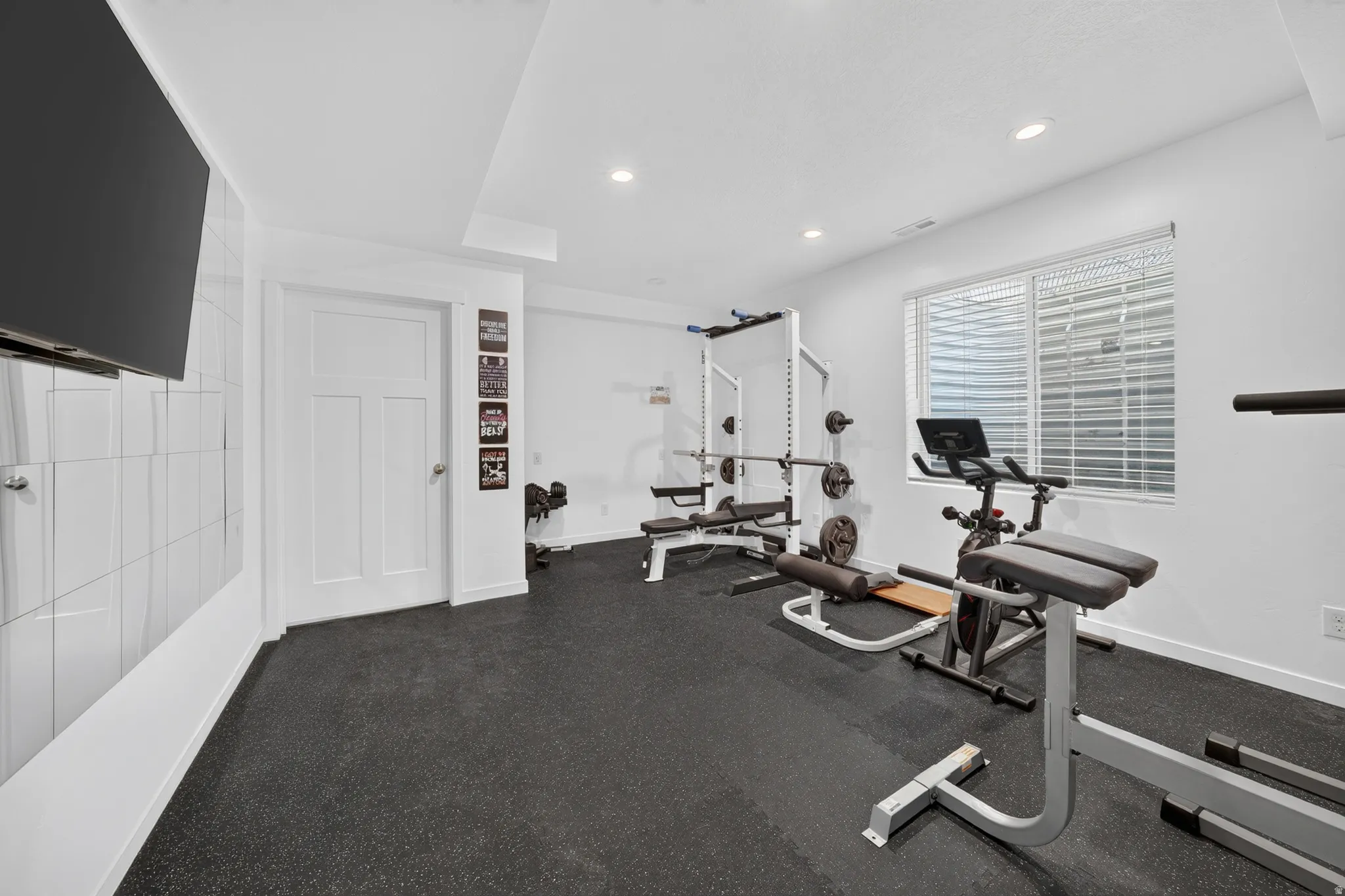 Recreational space with rubber flooring, recessed lighting, and a window with blinds