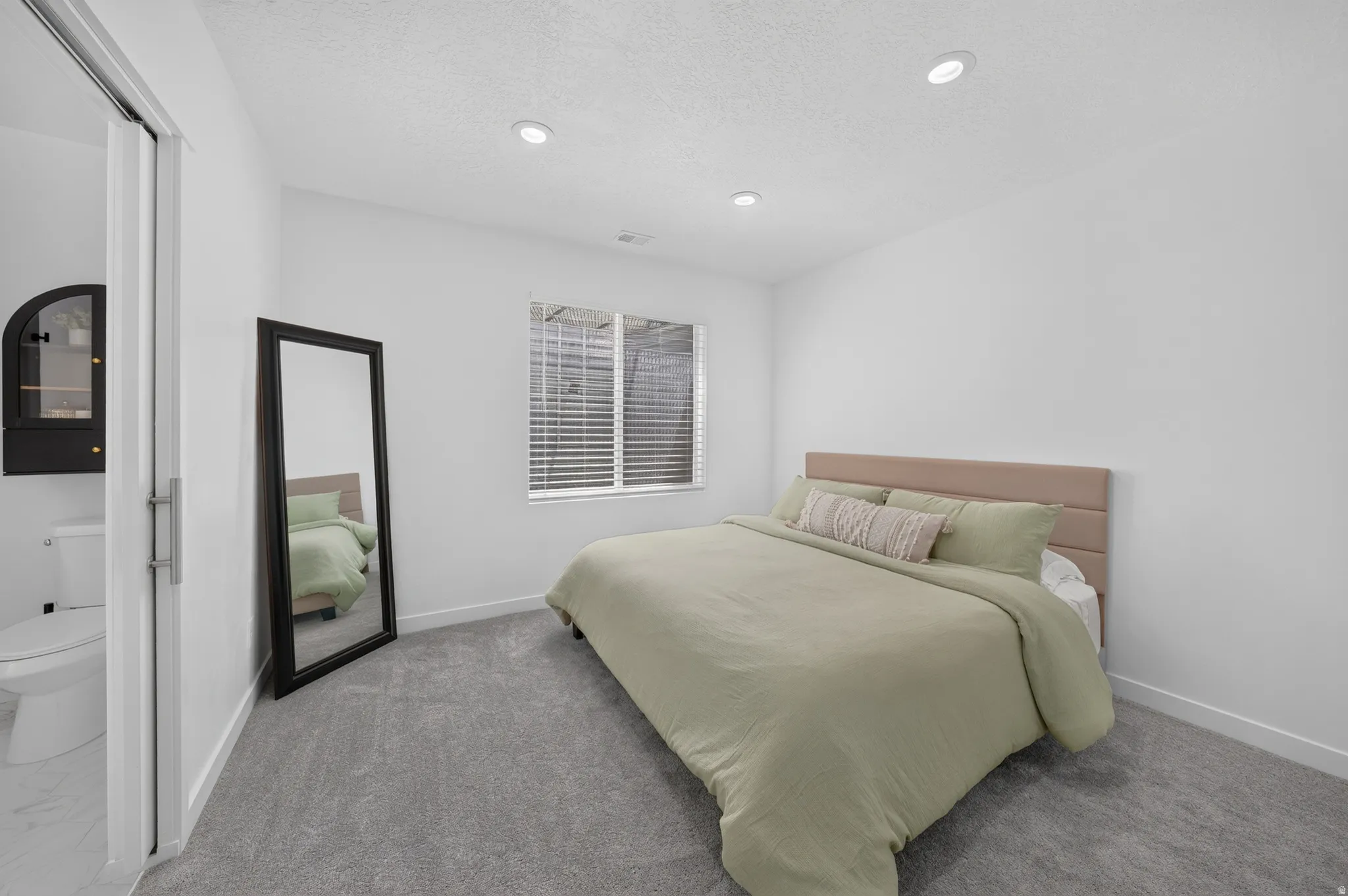 Carpeted flooring, recessed lighting, window with blinds, white walls, and a sliding door