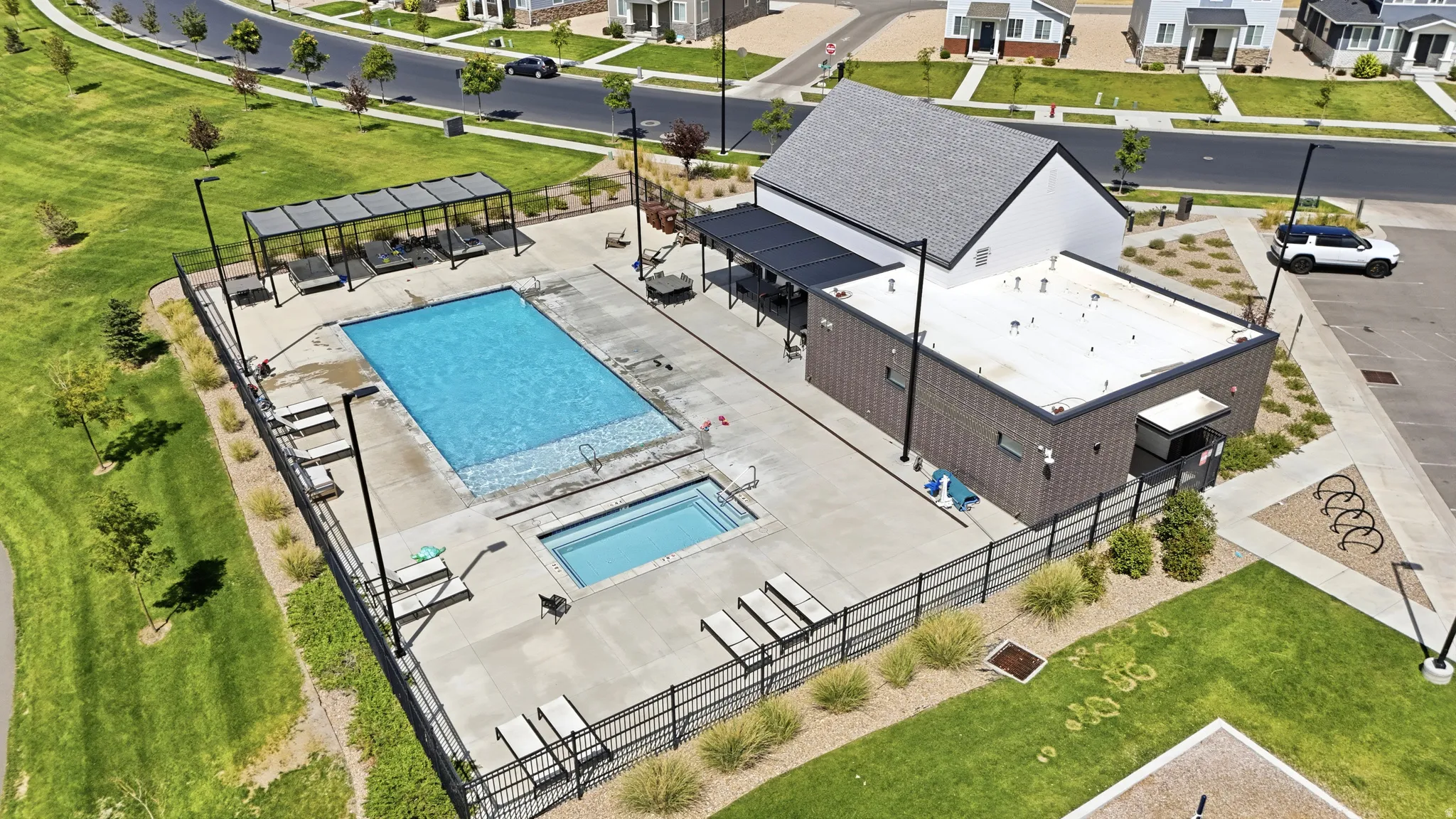 Recreational pool with integrated spa, adjacent covered lounge area, and modern building with covered patio