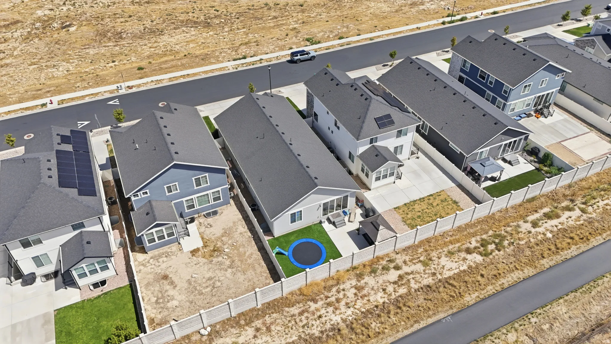 Newly constructed residences featuring dark shingle roofing, light-colored fencing, and paved driveways