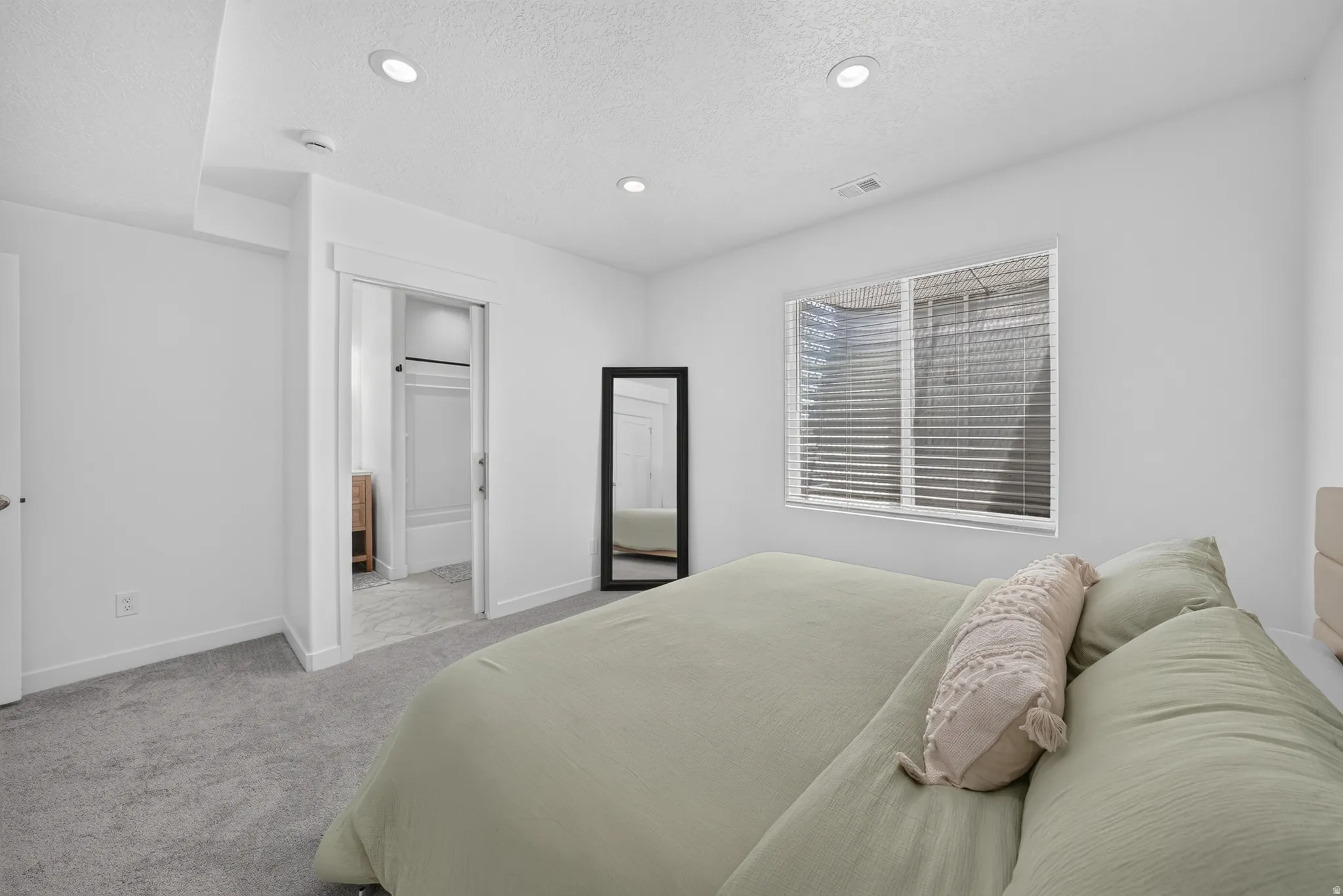 Recessed ceiling lighting, white walls, gray carpet, and a window with blinds