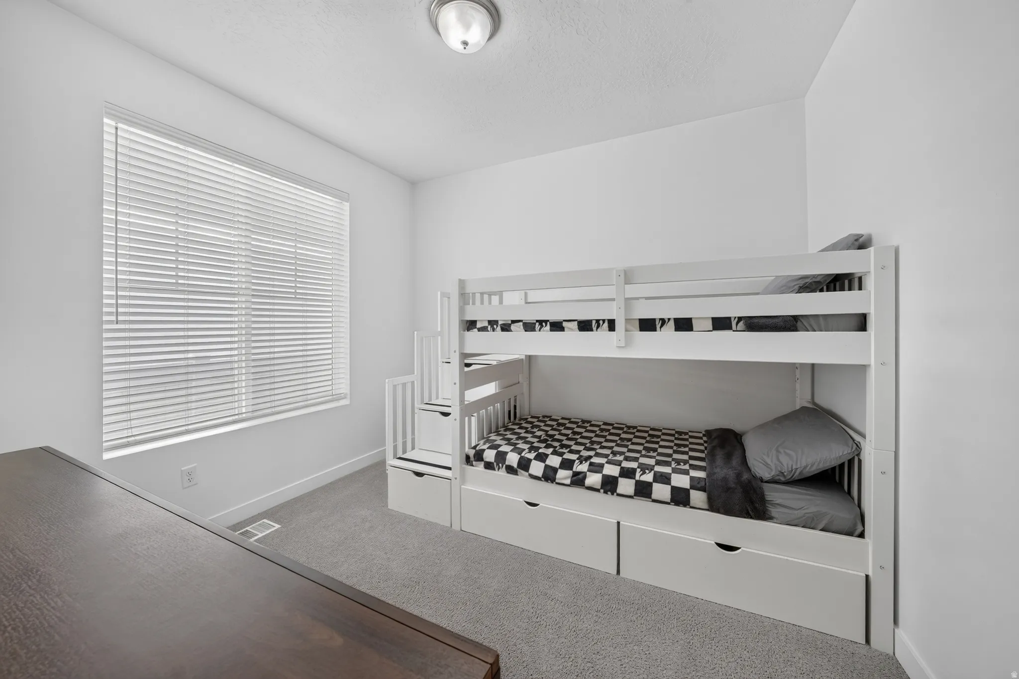 Carpeted room with a large window featuring blinds and a flush mount ceiling light