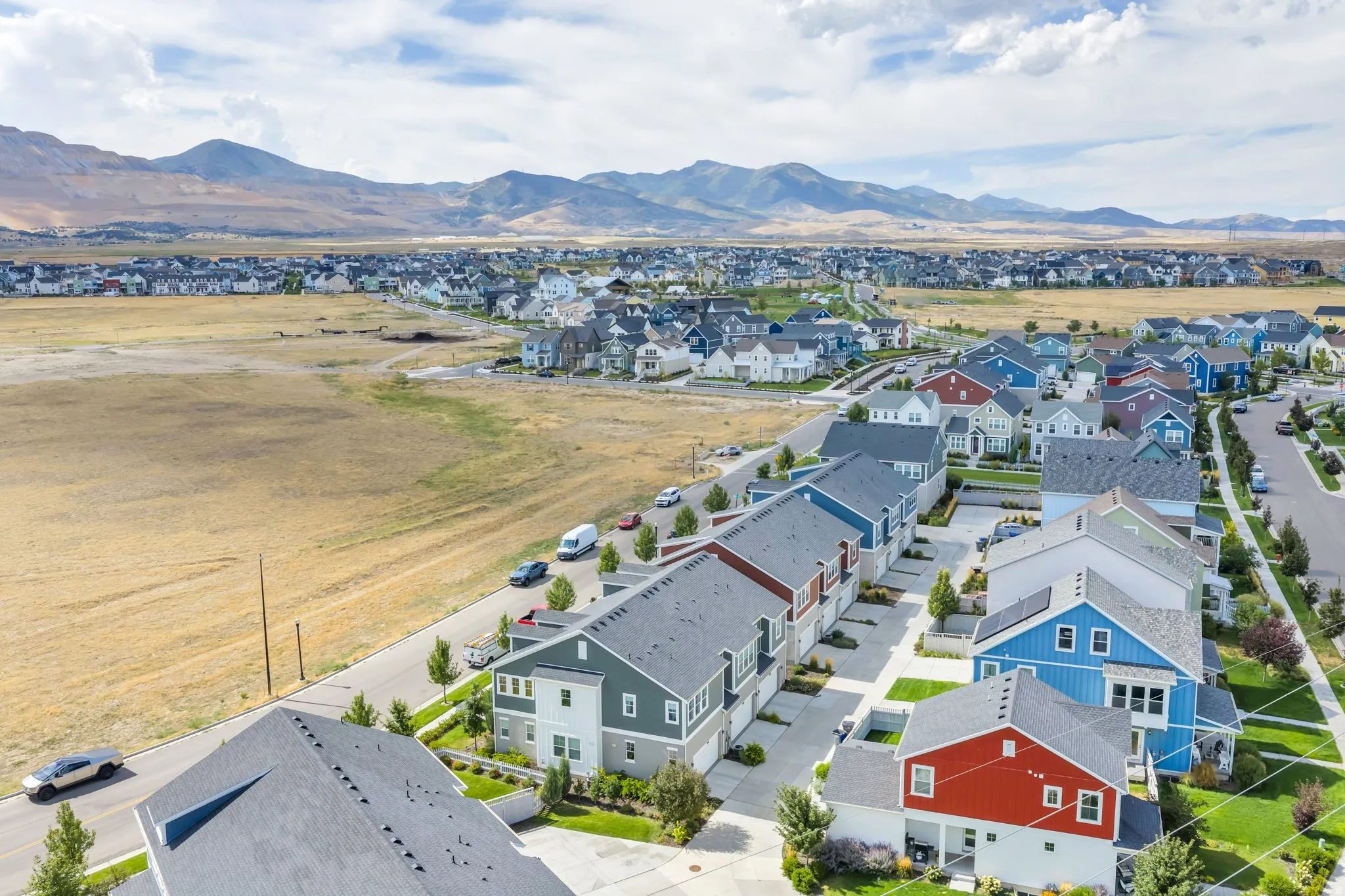 Newly constructed residences with varied exterior finishes, paved roads, maintained landscaping, and mountain backdrop