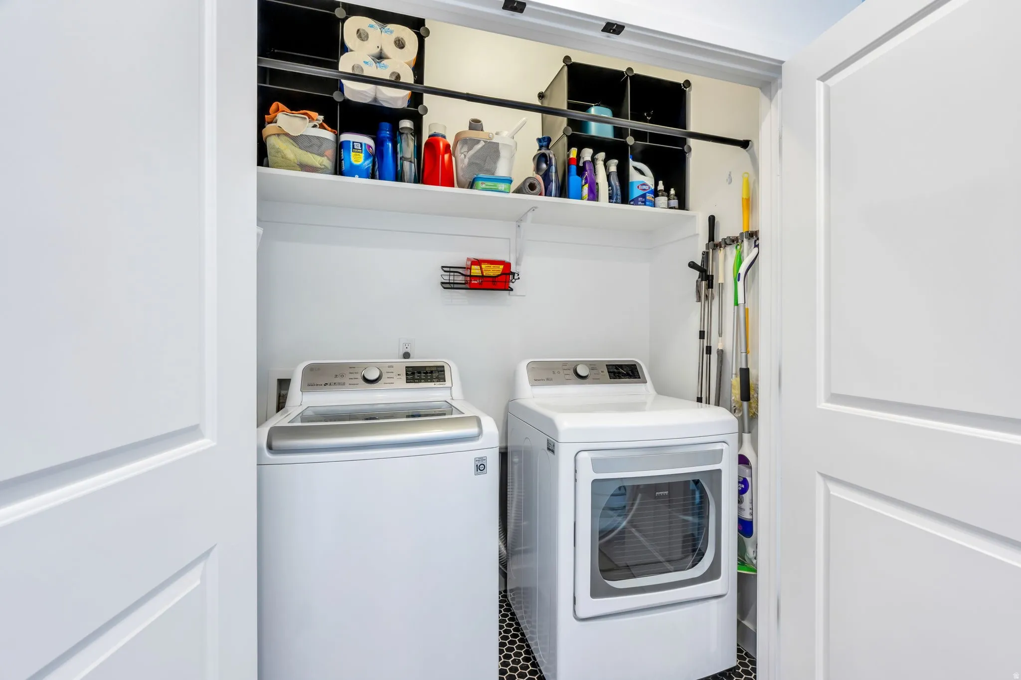Laundry area featuring a built-in shelf, black hexagonal floor tiles, and bi-fold doors