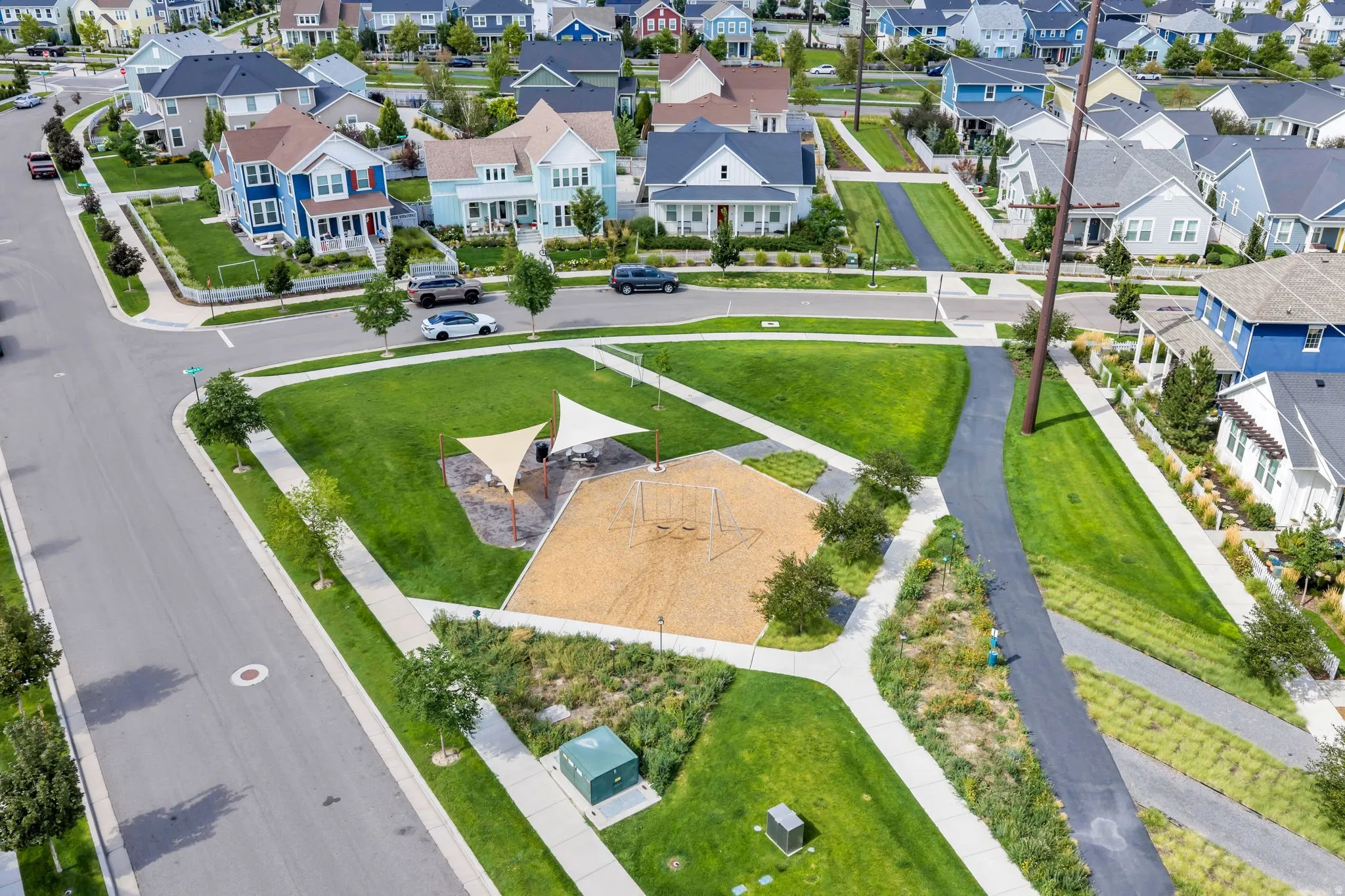Community greenspace featuring a playground with shade structures and a walking path