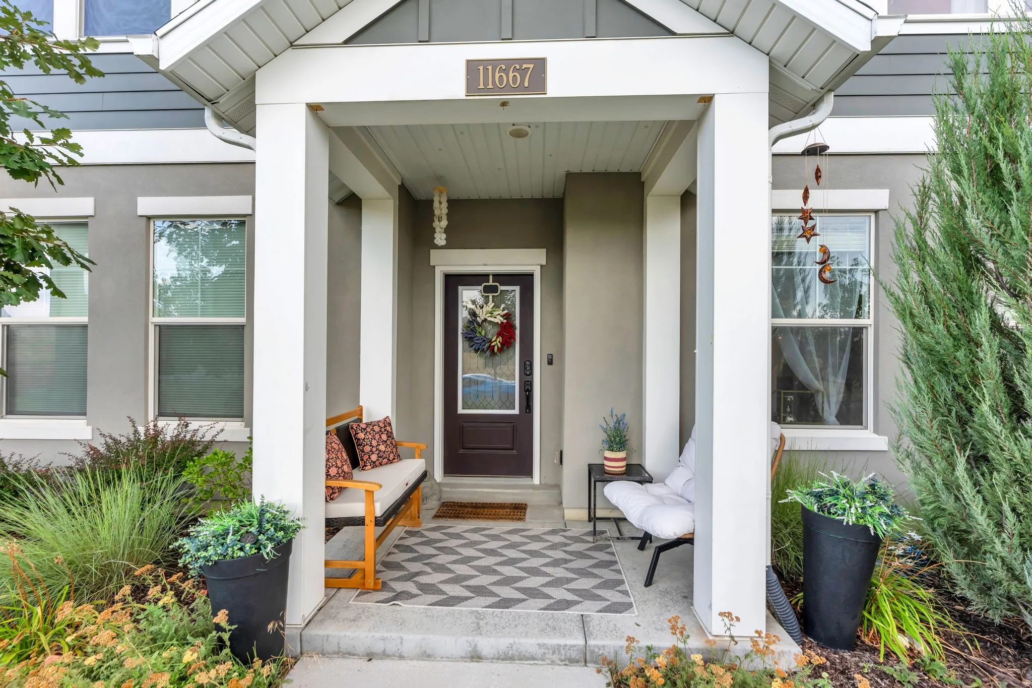 Covered front entry featuring a paneled door with decorative glass, multiple windows, and a portico with white columns