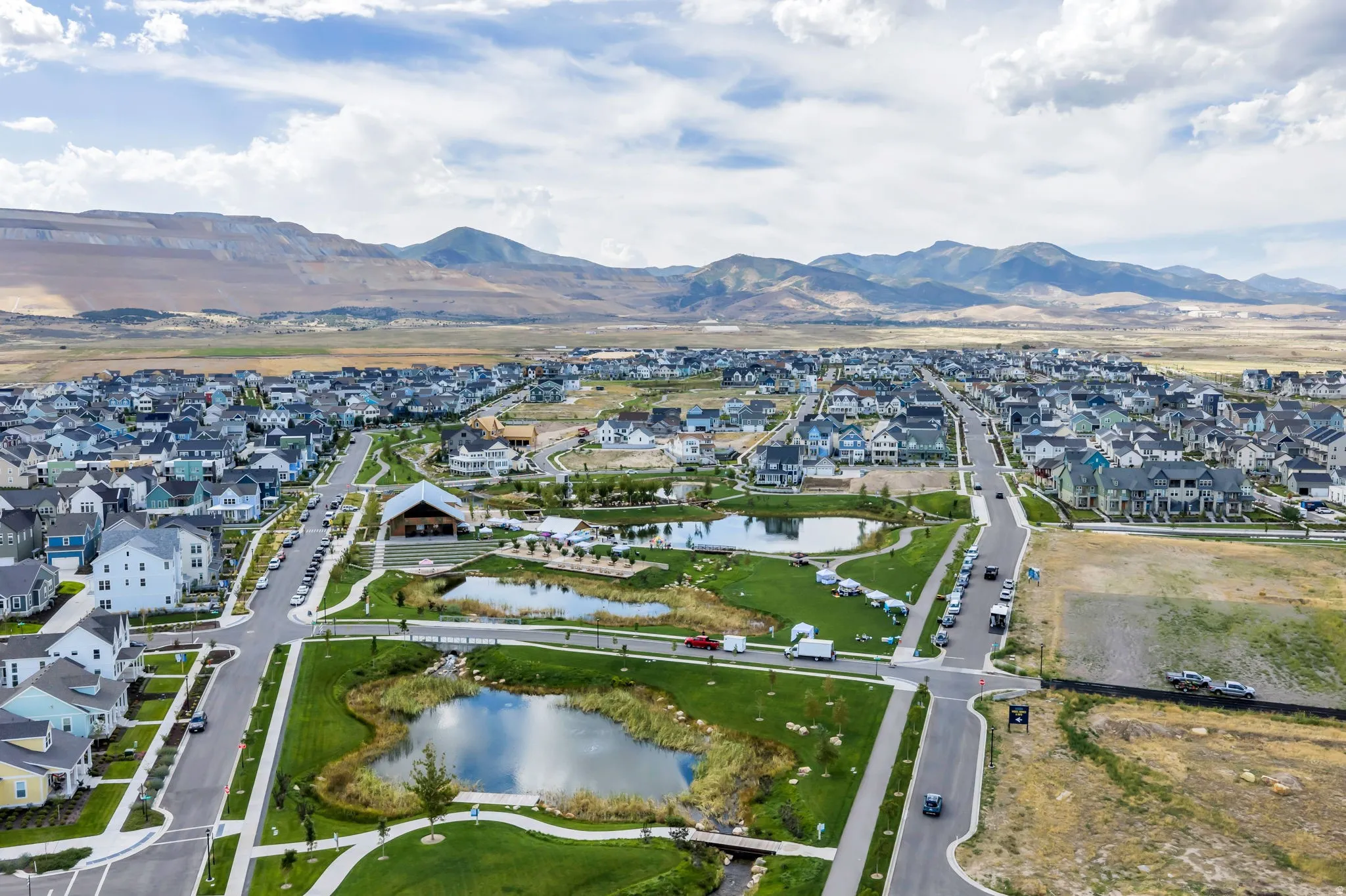 Community with residential homes, green spaces, and water features, set against a mountain backdrop