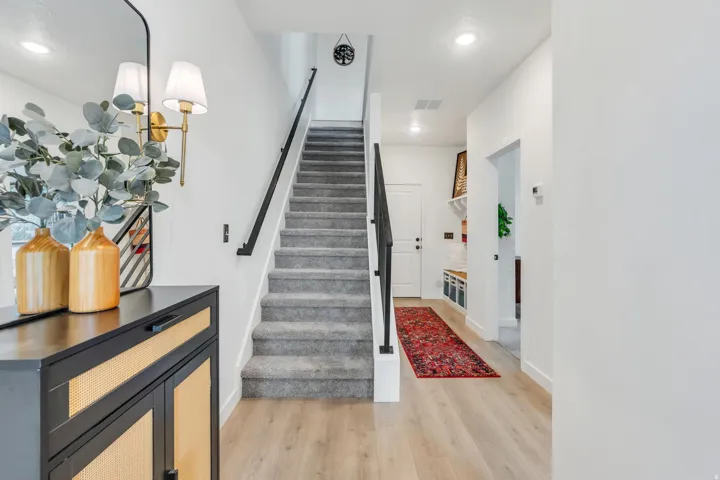 Wood-finish flooring, recessed lighting, and a carpeted staircase with a dark handrail