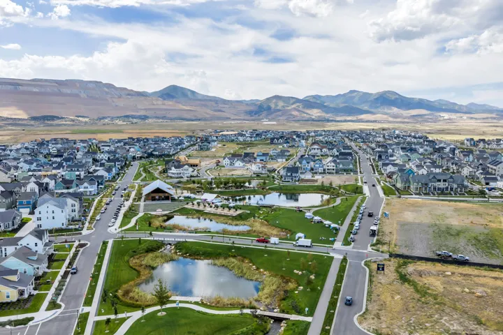 Community with residential homes, green spaces, and water features, set against a mountain backdrop